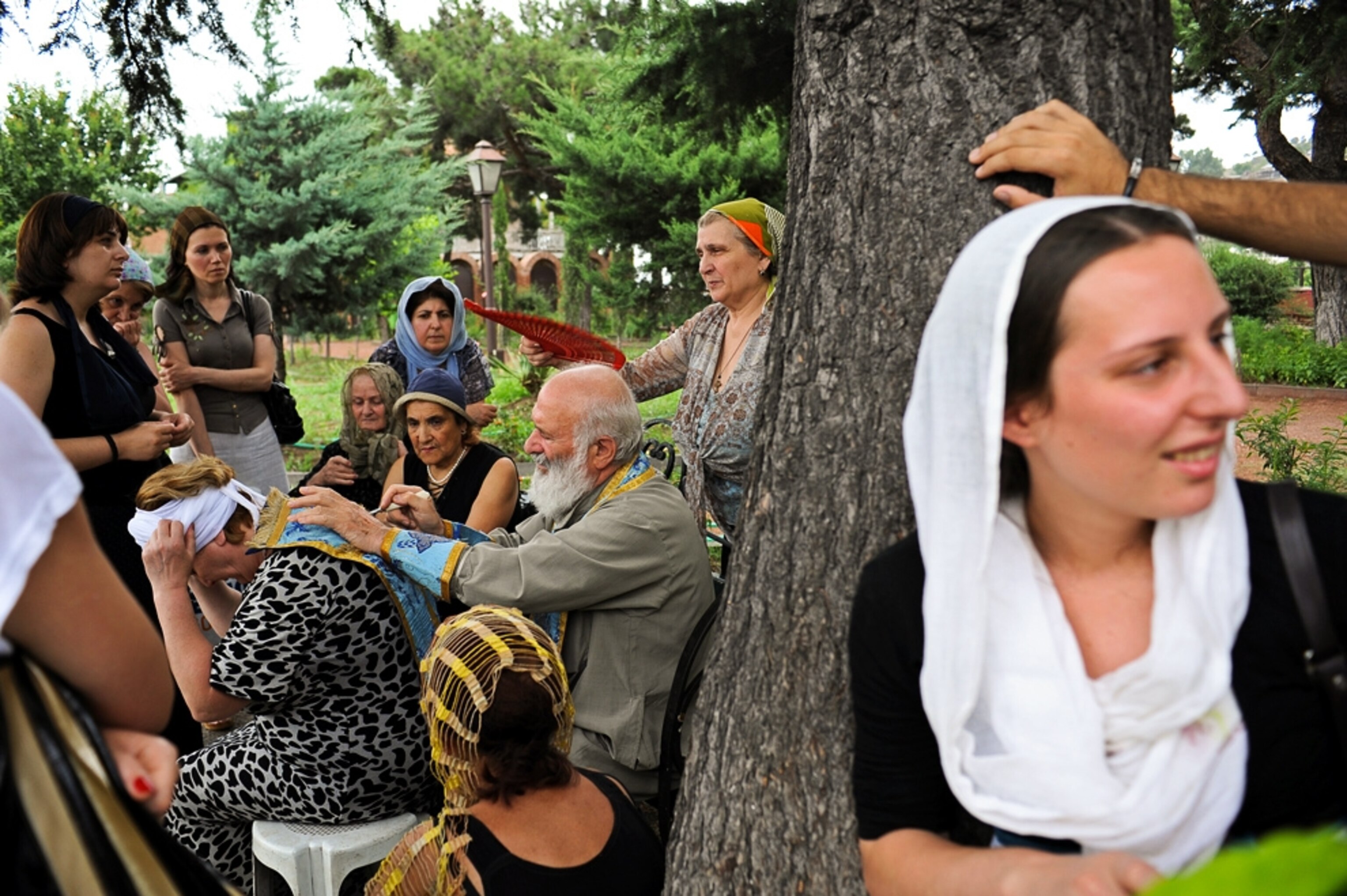 A woman looks on while a priest offers a blessing in Tbilisi, Georgia