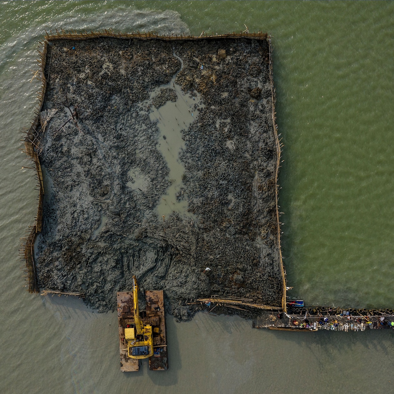 Excavator moves mud onto a flooded cemetery.