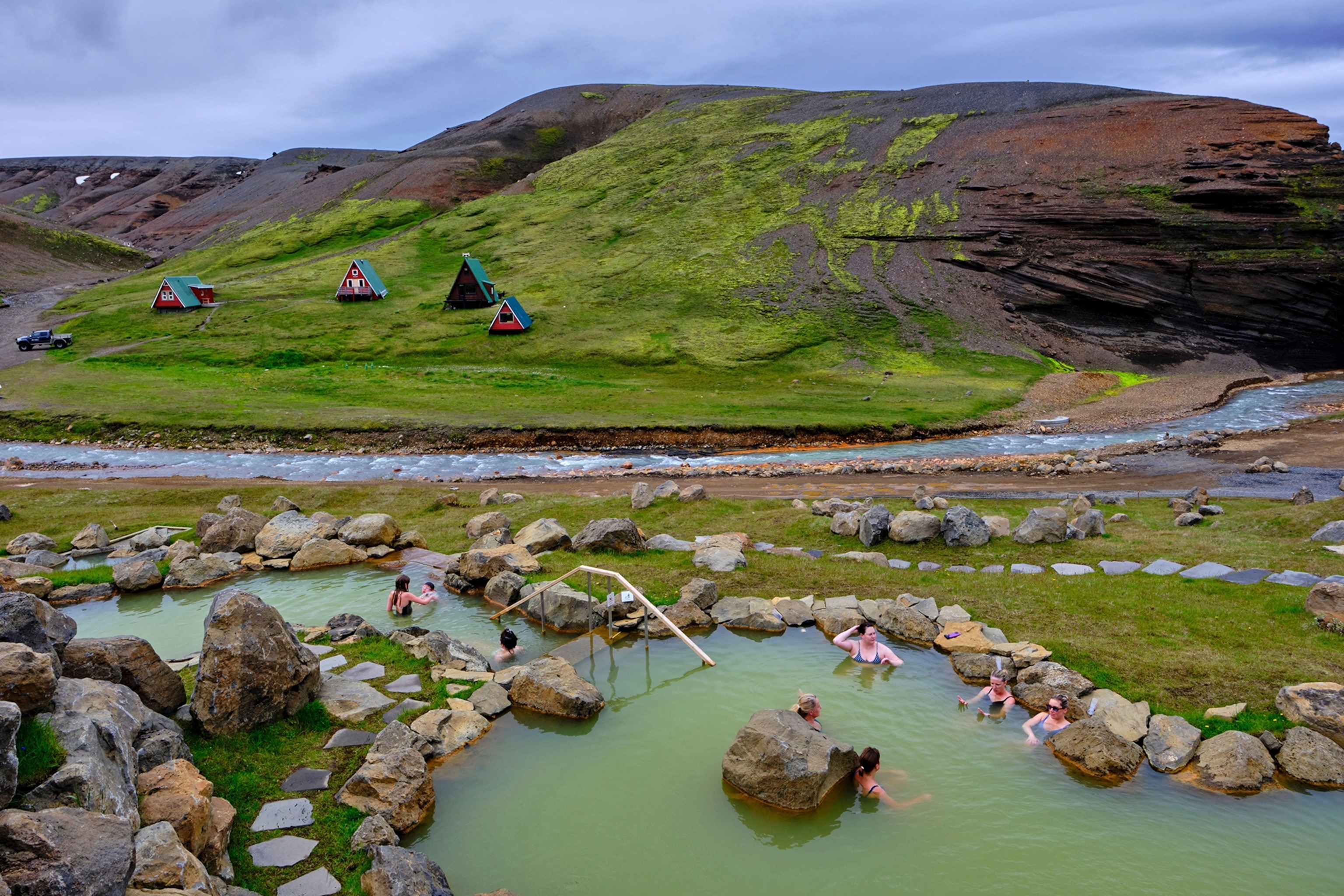 A calm and still lagoon set into the flat, rocky landscape with a hill in the background.