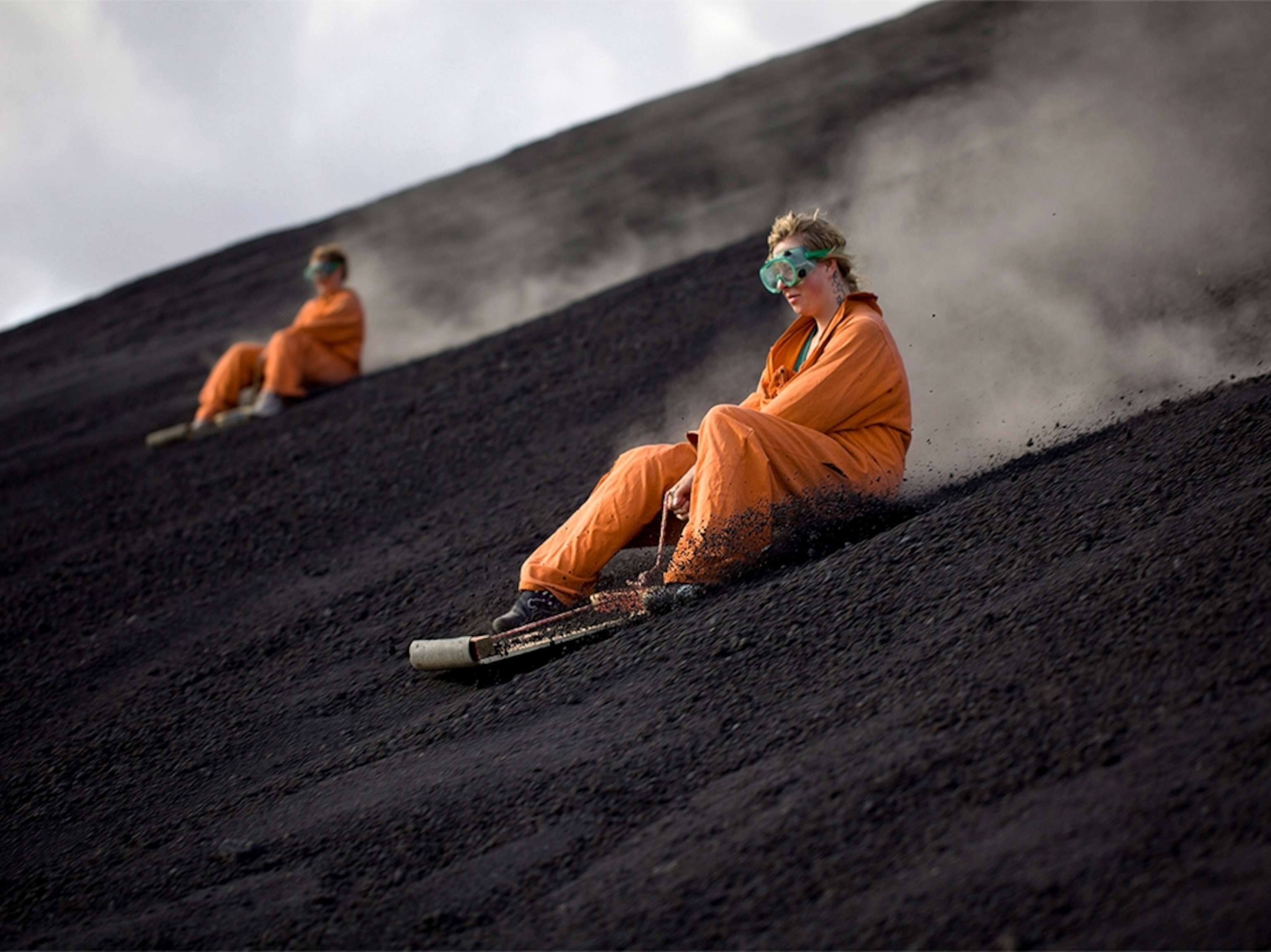 a boy and girl volcano boarding on the Cerro Negro volcano in Nicaragua