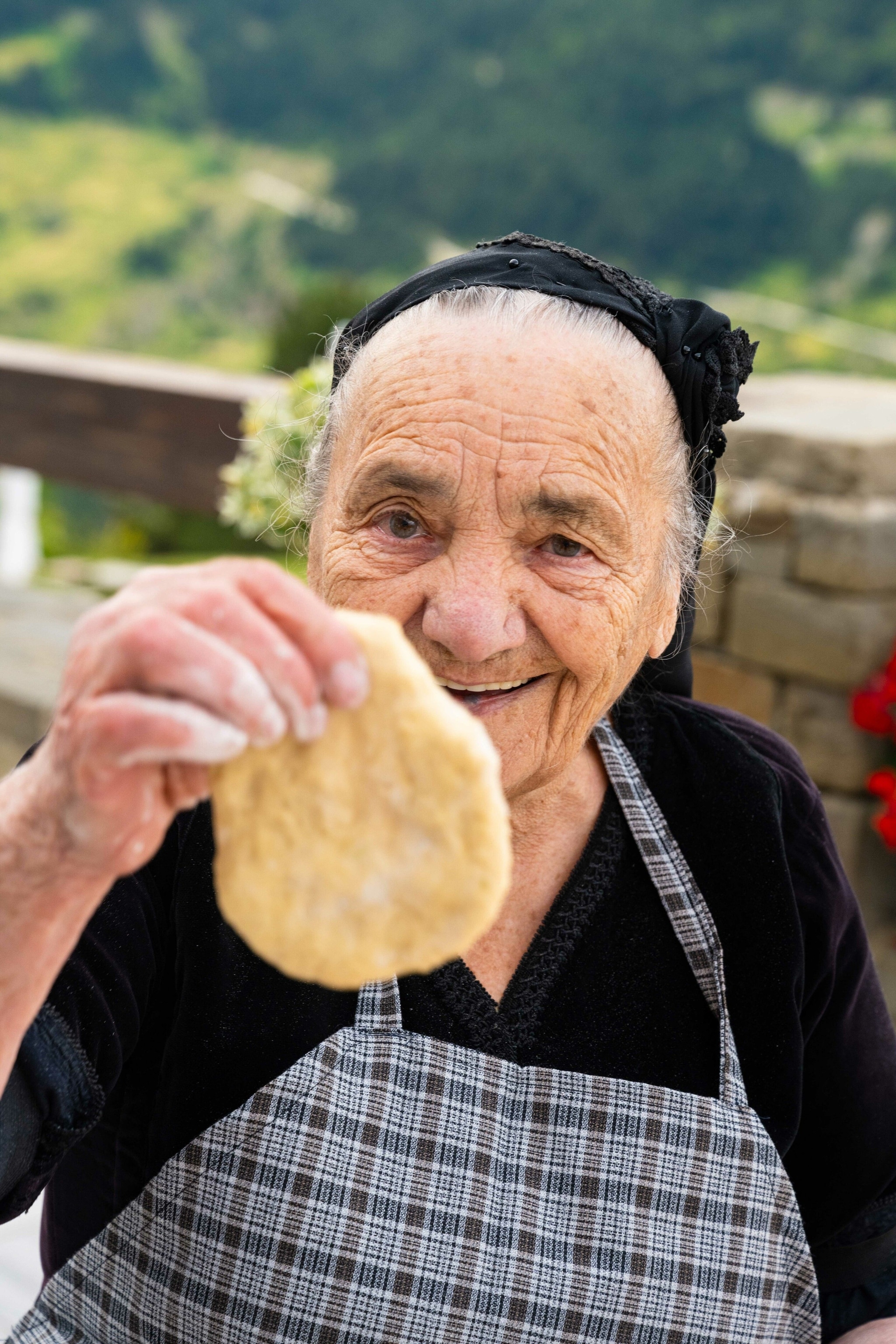 A woman holding a traditional pie. It is shaped like a 2D pear - thinner at the top and fatter at the bottom.