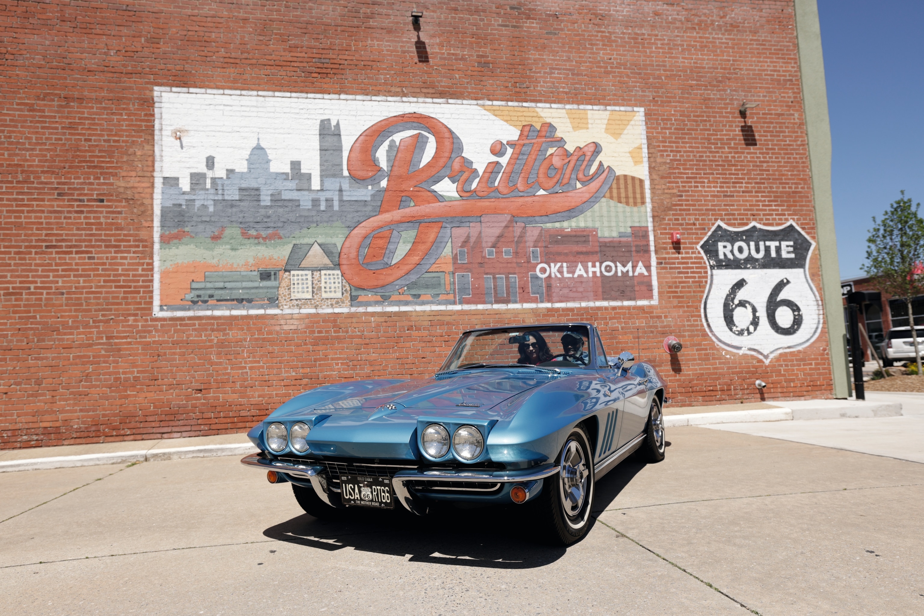A car stands in front of a red brick building with a colourful mural of the Britton district.
