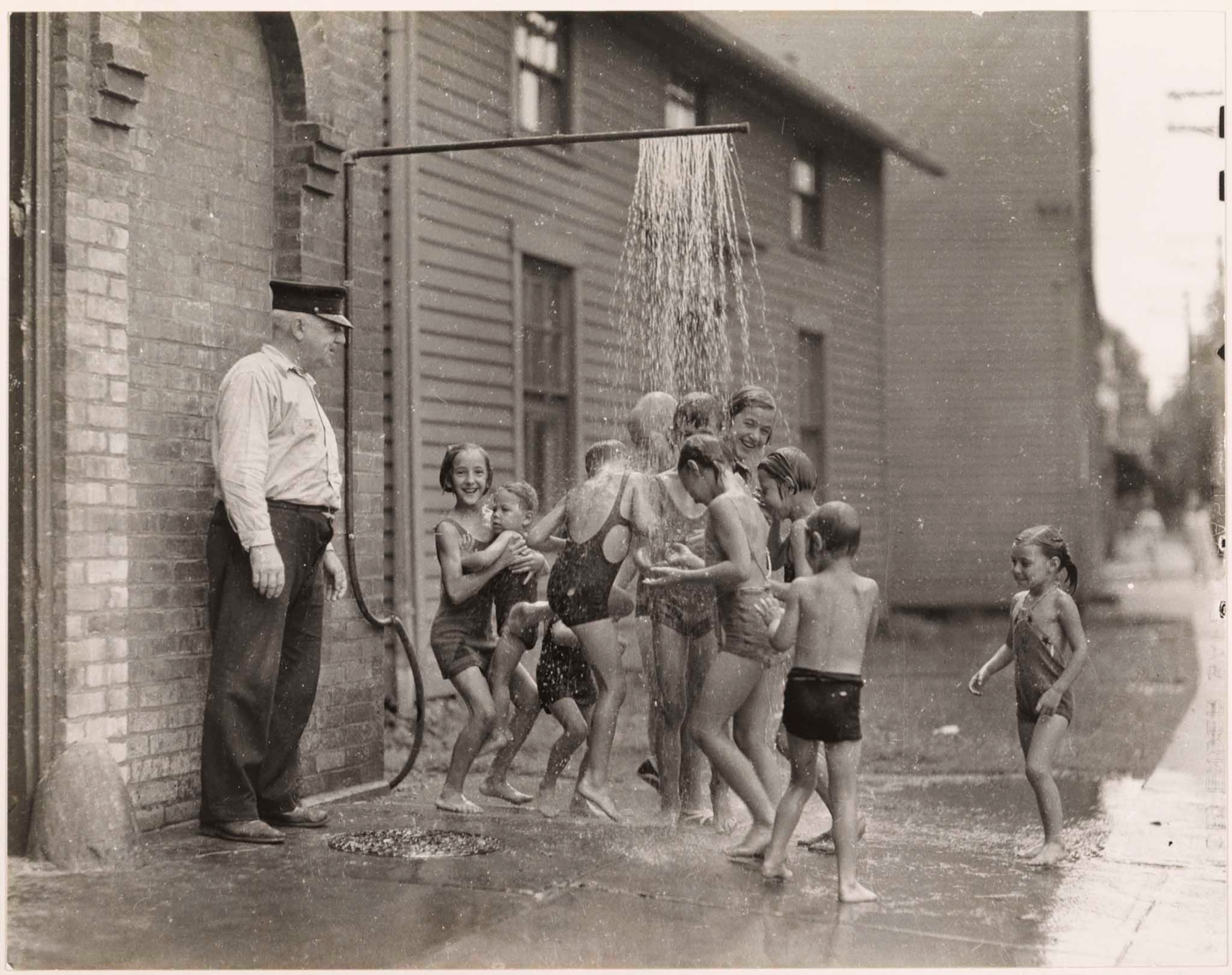 children cooling off from summer heat under a sidewalk spray
