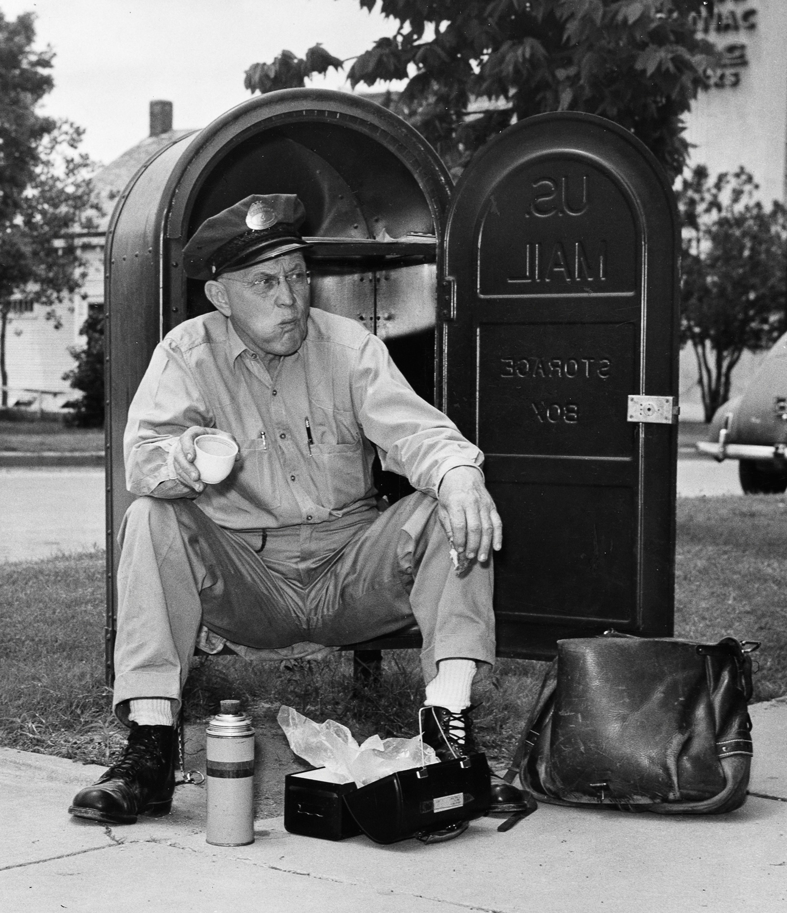 A letter carrier eats lunch in a mailbox.