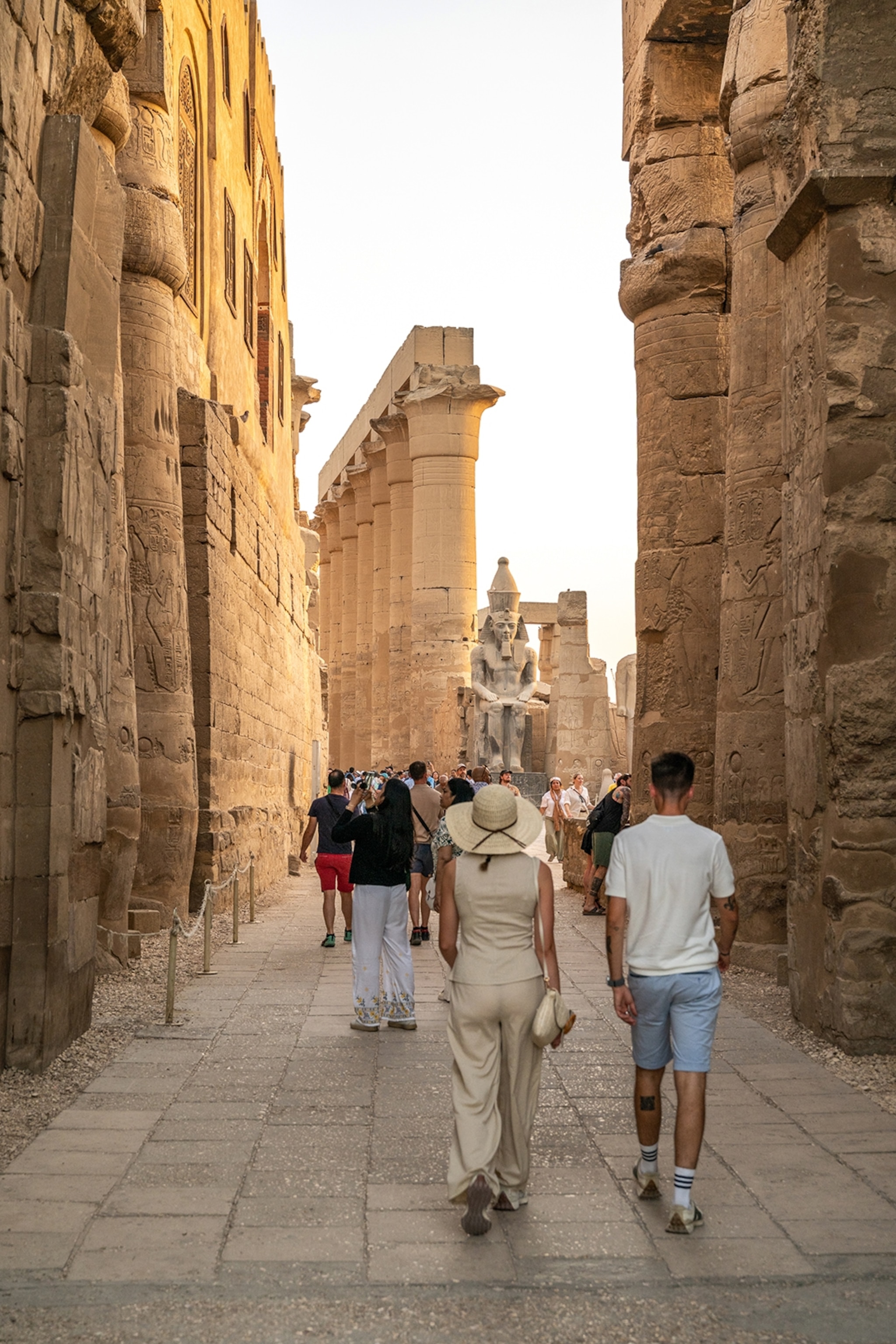 Visitors strolling past massive stone pillars, which are part of an ancient temple.