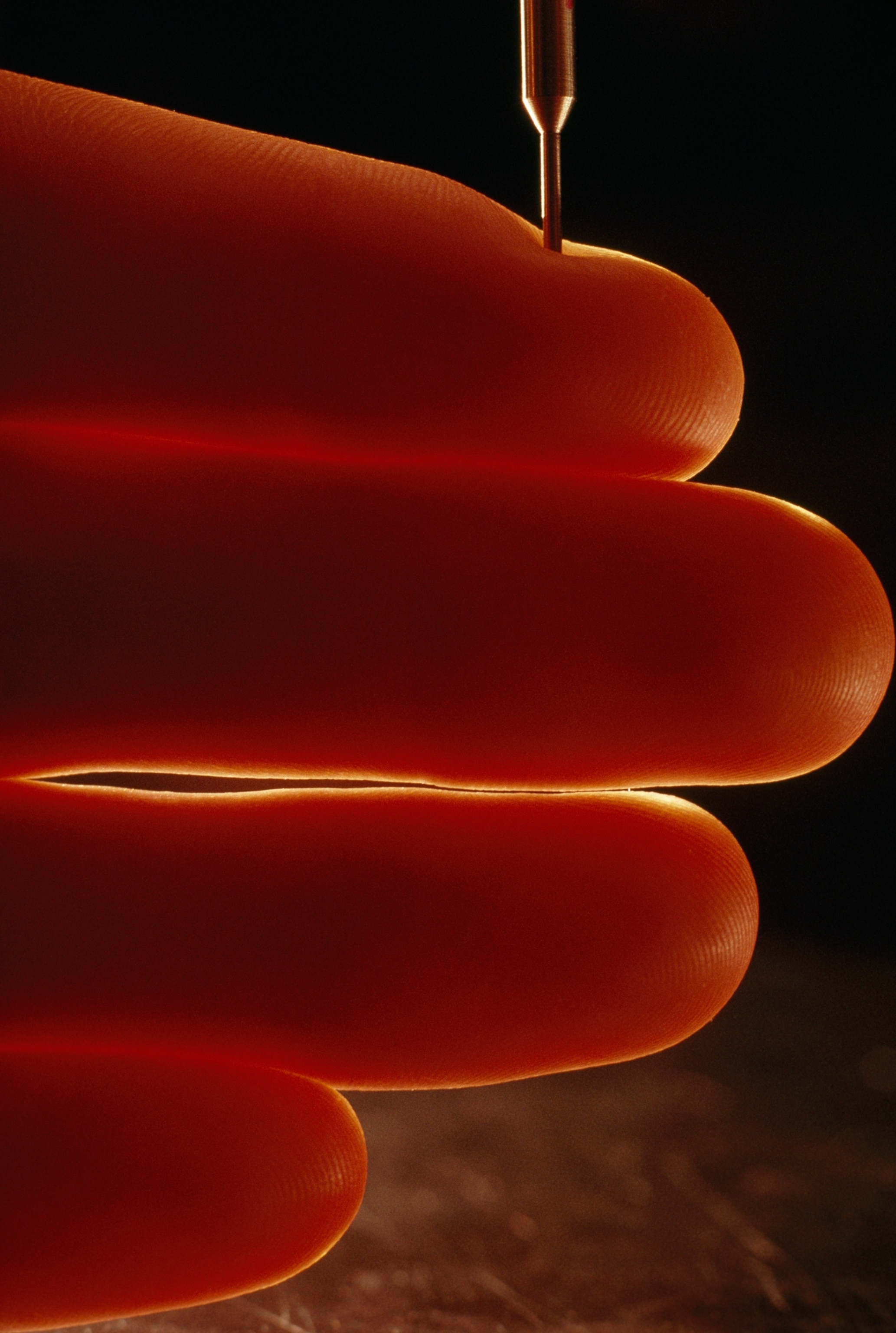 A close-up view of fingers as a pin is pressed into the skin