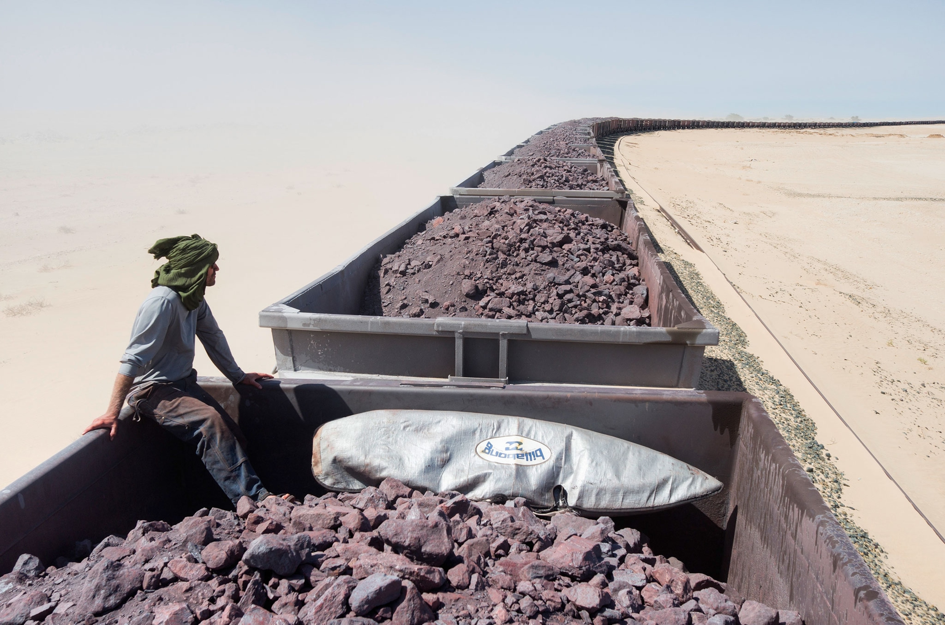 surfer hitching a ride on train car in Mauritania