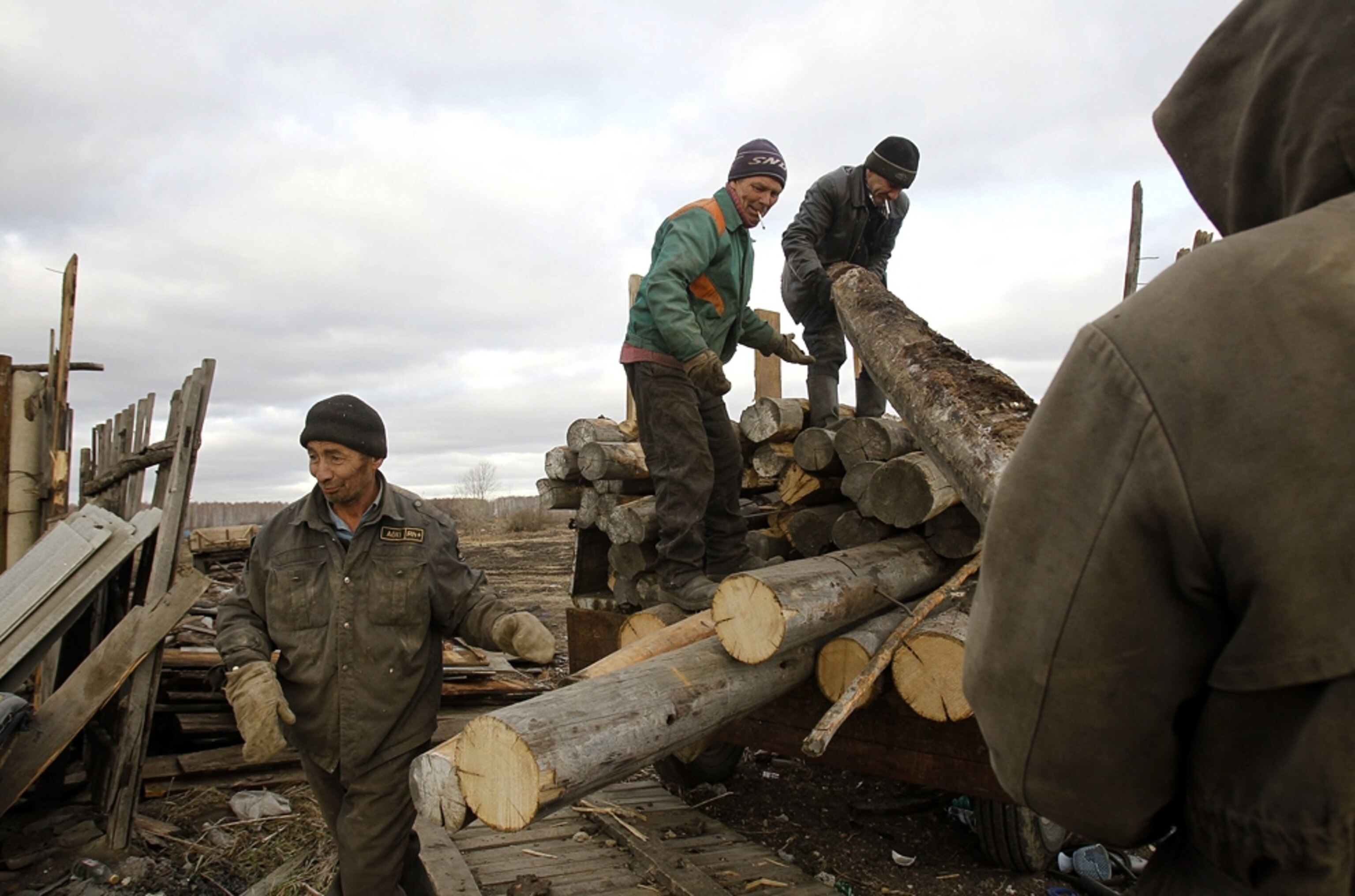 Men disassemble a house and load the logs onto a truck.