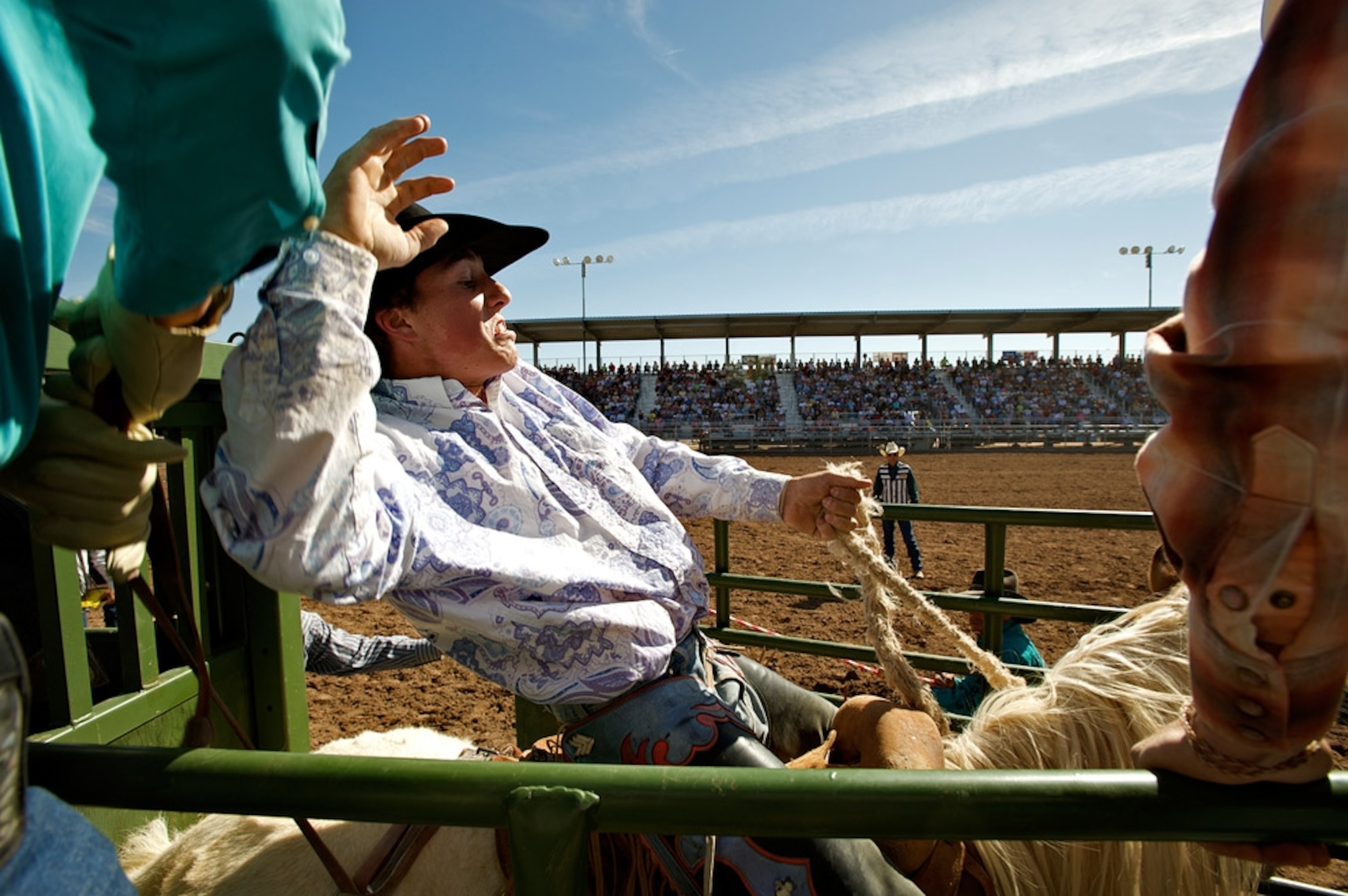 A teenager on a horse in a rodeo enclosure