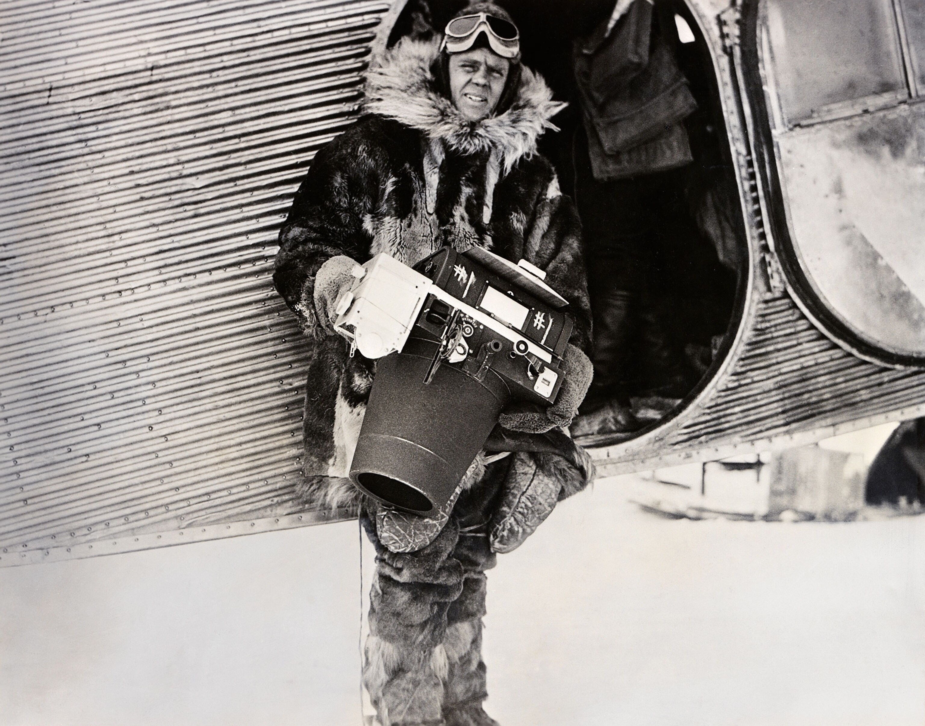 a man with with a large camera next to a plane.