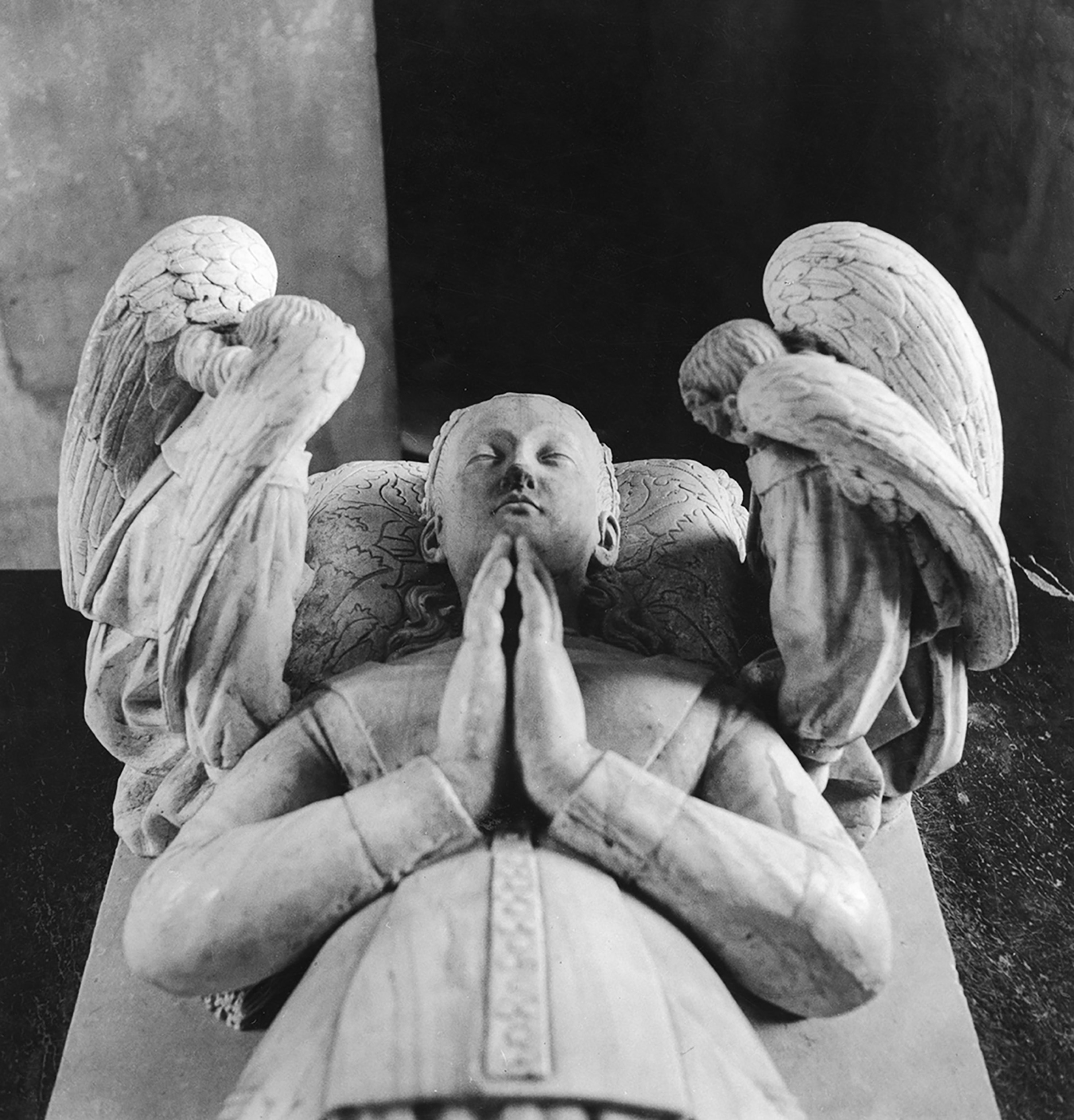 Black and white image of woman with hands clasped and angels looking over her.