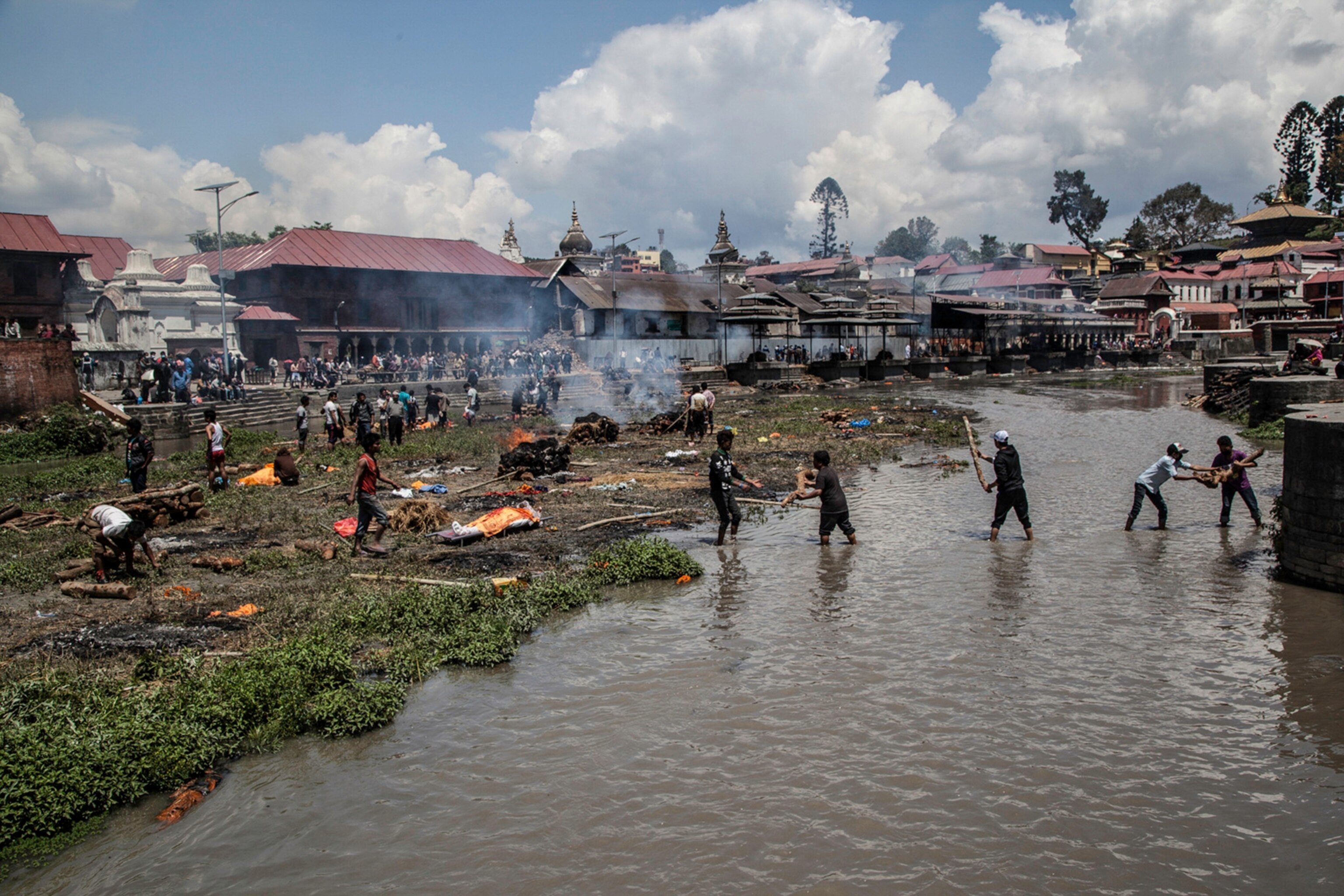 Smoke rises from burning funeral pyres during the cremation of earthquake victims