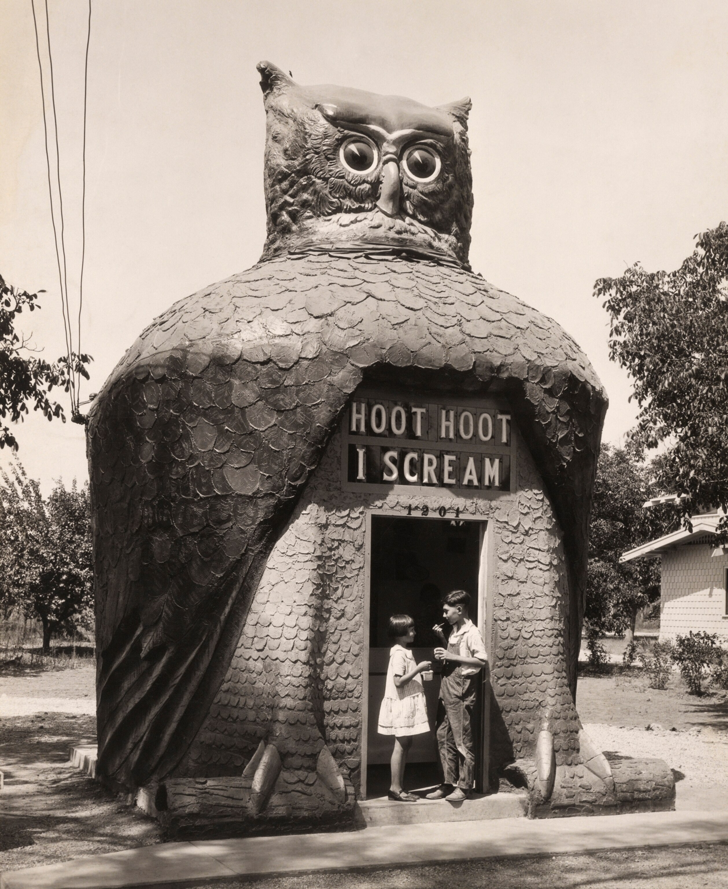 Children outside an ice cream parlor built in the shape of an owl.
