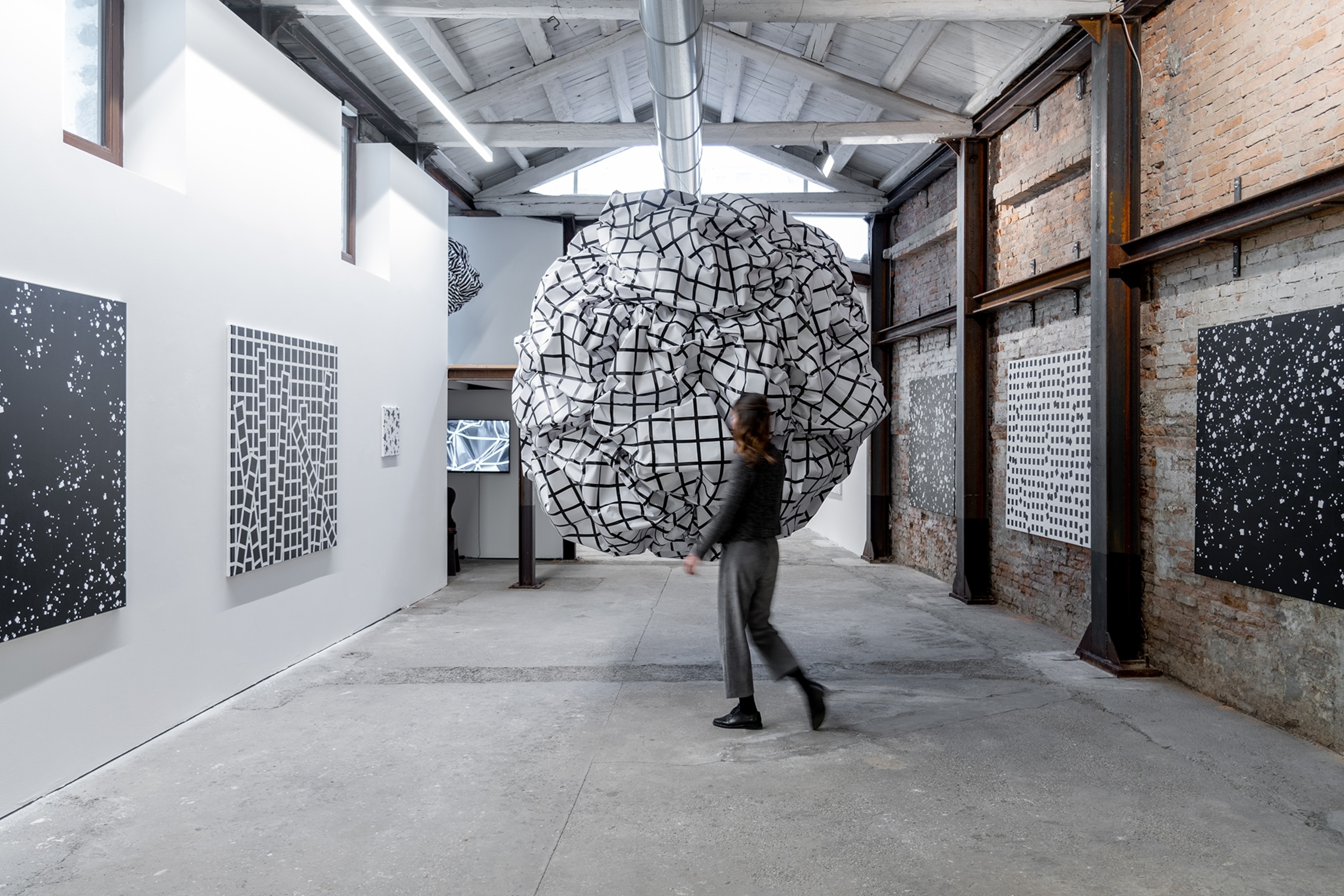 A simplistic gallery with concrete floors and art hung on the walls.