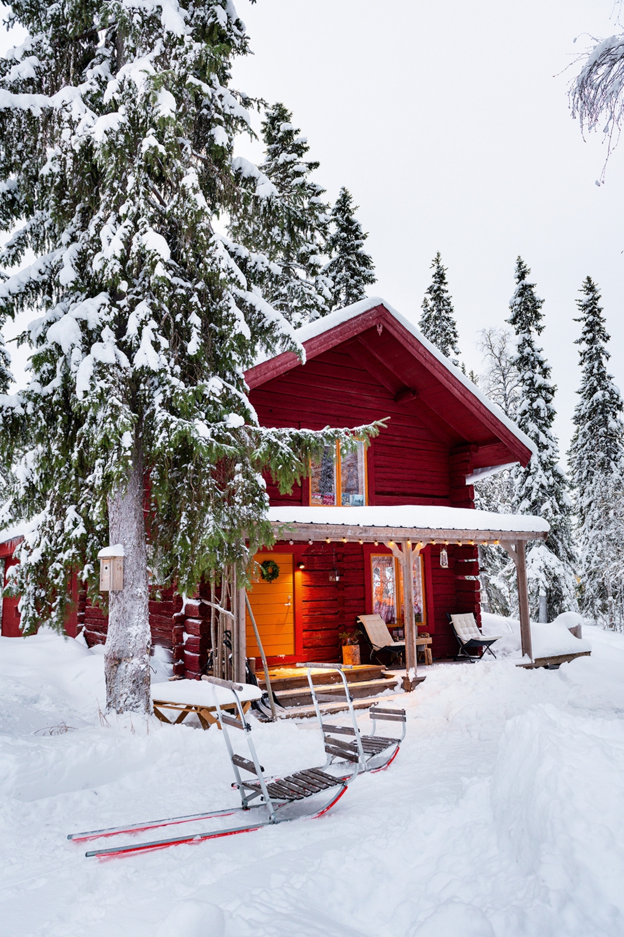 A gable-roofed, wooden blockhouse peaking through snowy trees.