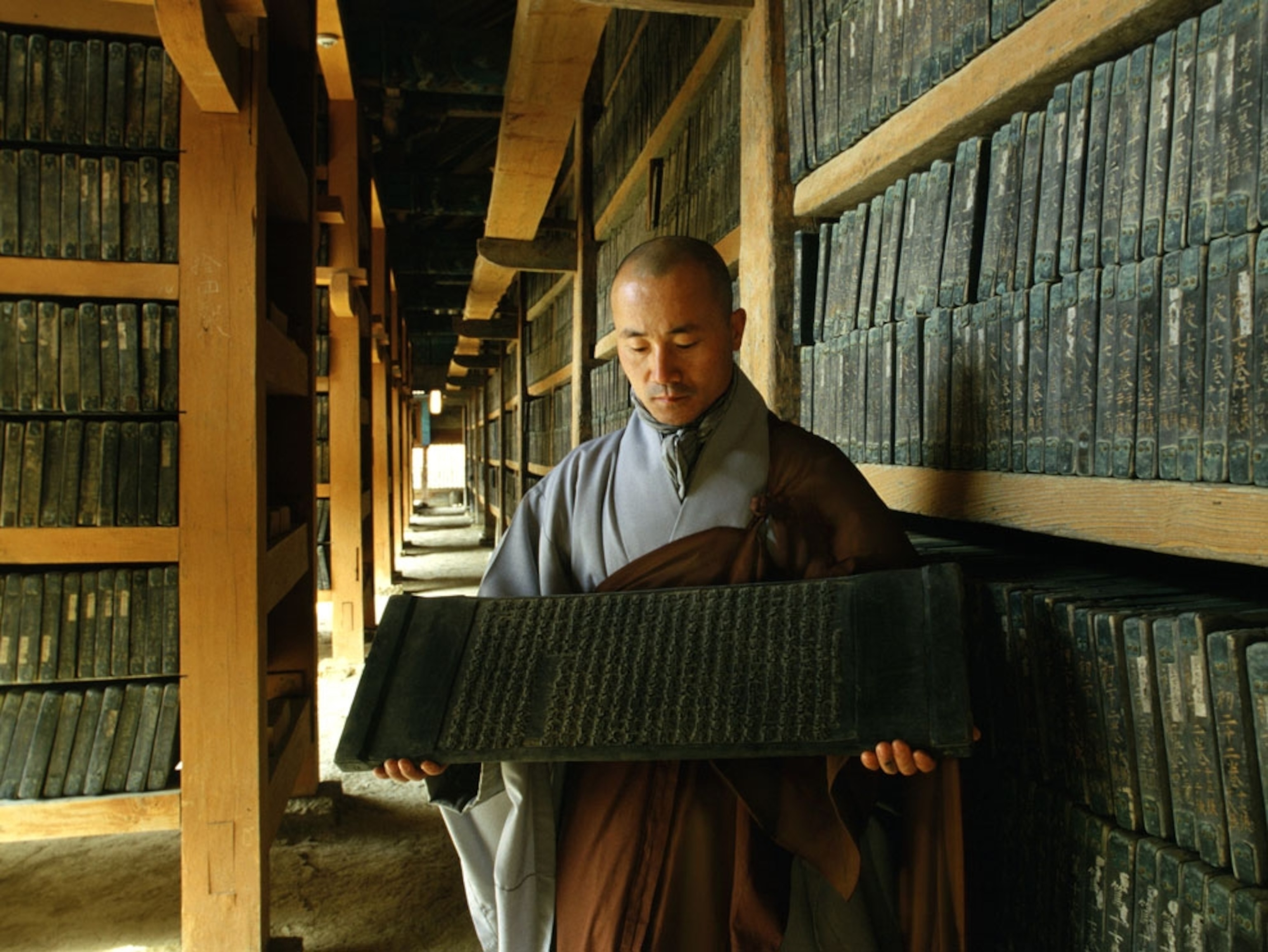 A Buddhist monk displaying a hand-carved wooden tablet