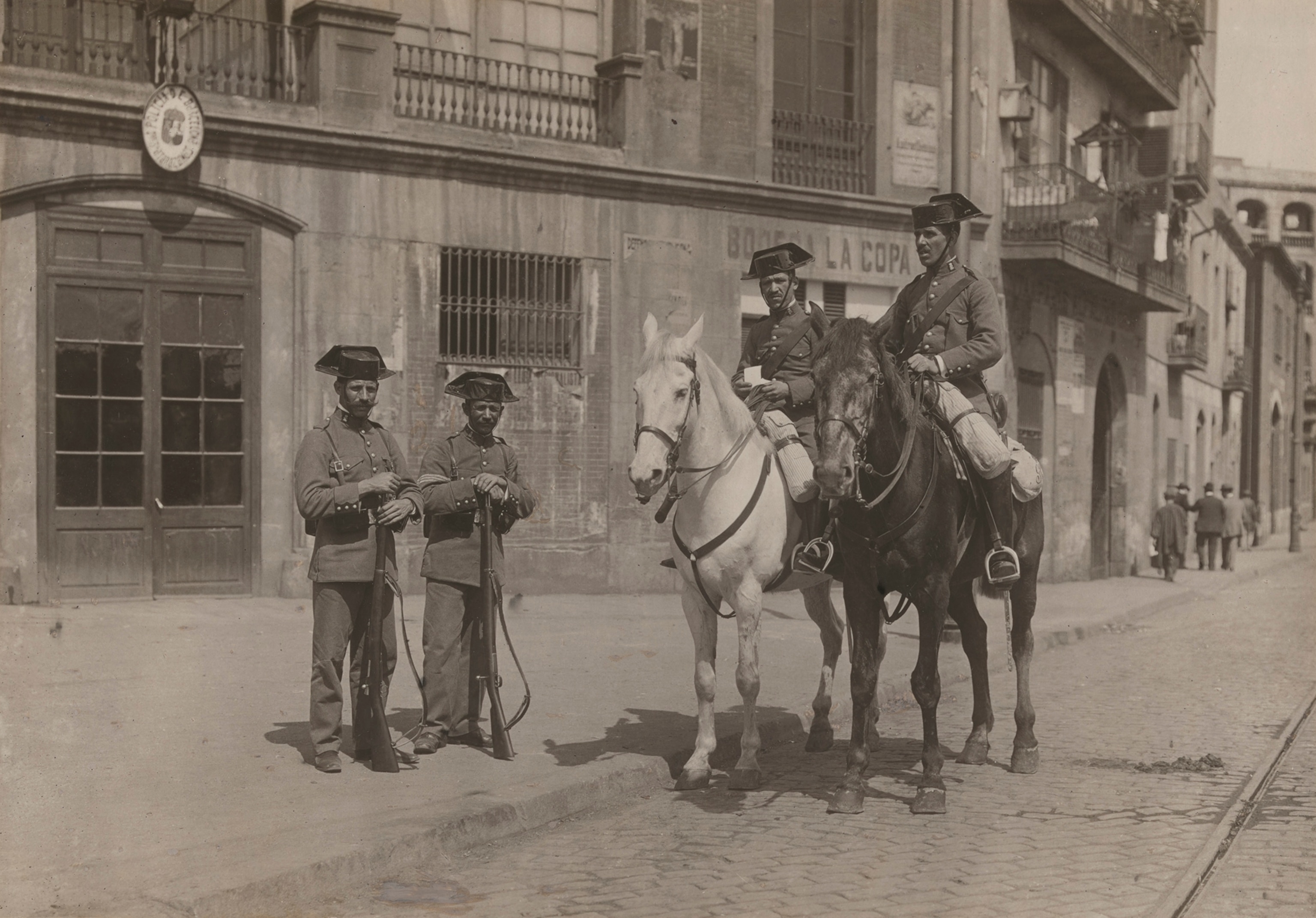 Members of the local police force, two mounted, pose on a street.