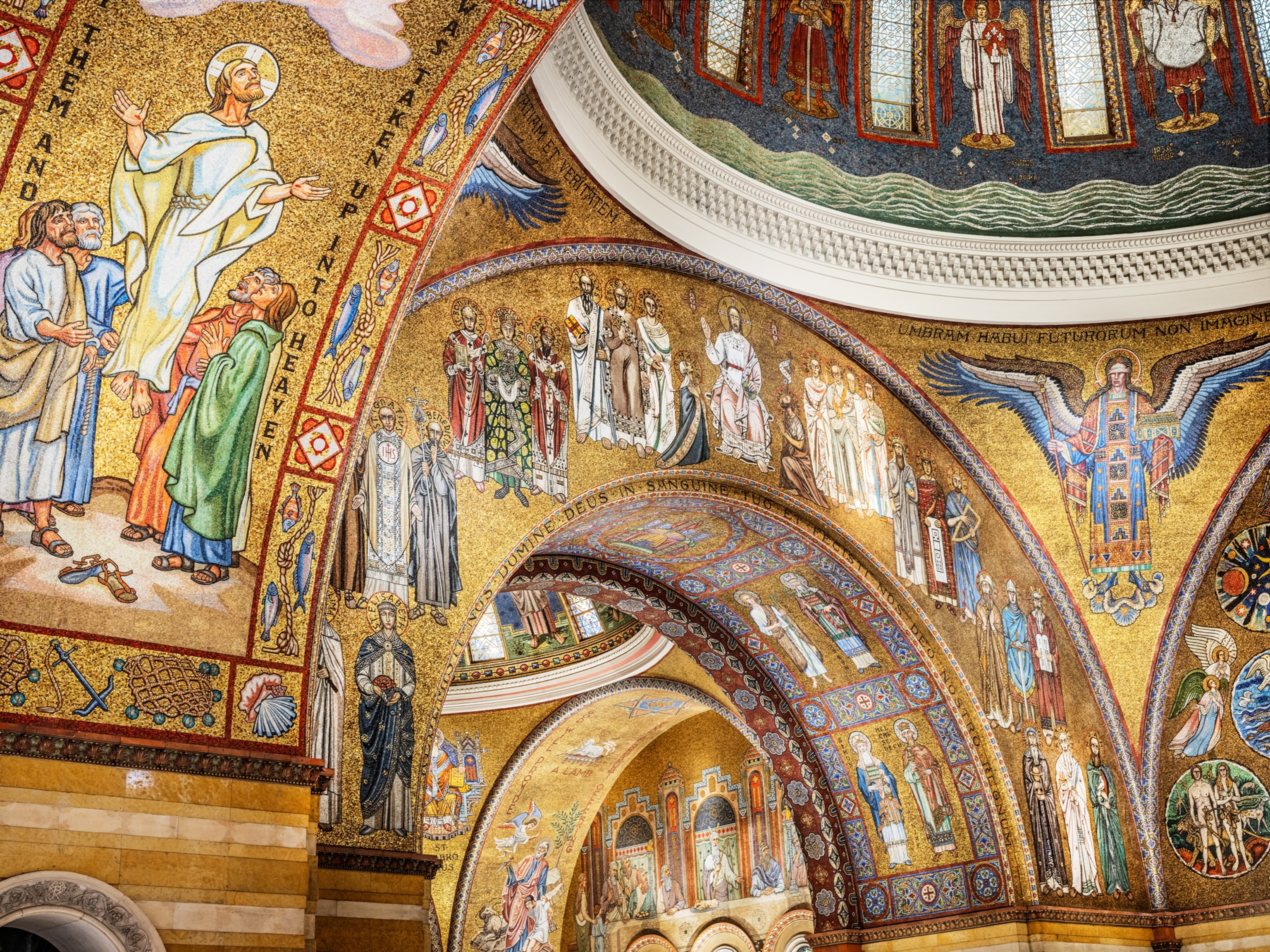 A large mosaic spans across several rooms with large arches connecting the rooms. The mosaics are primarily a yellow gold color with religious symbols and people spread across the walls and arches.
