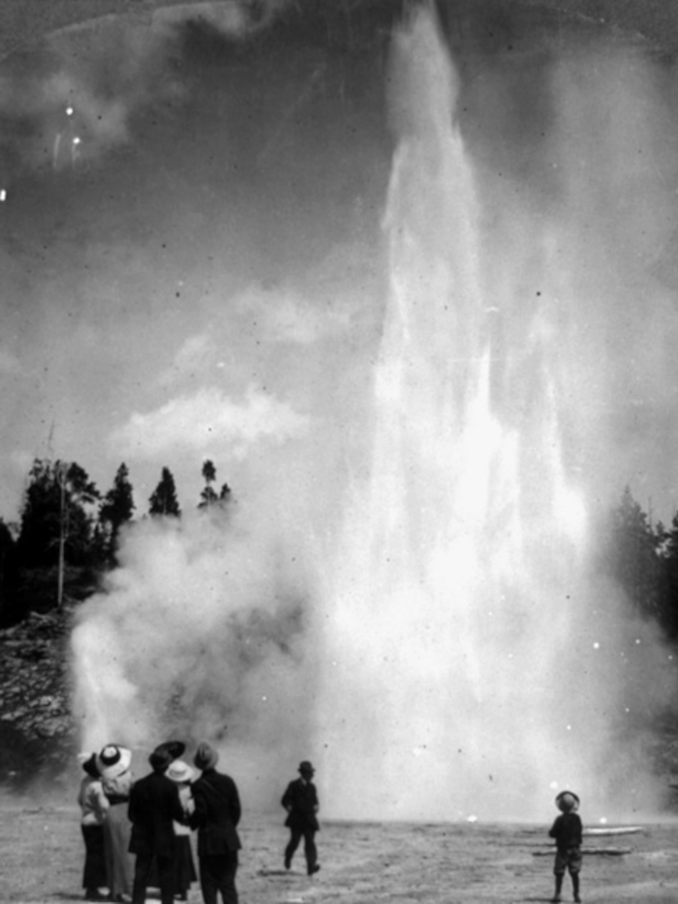 People watching an erupting geyser
