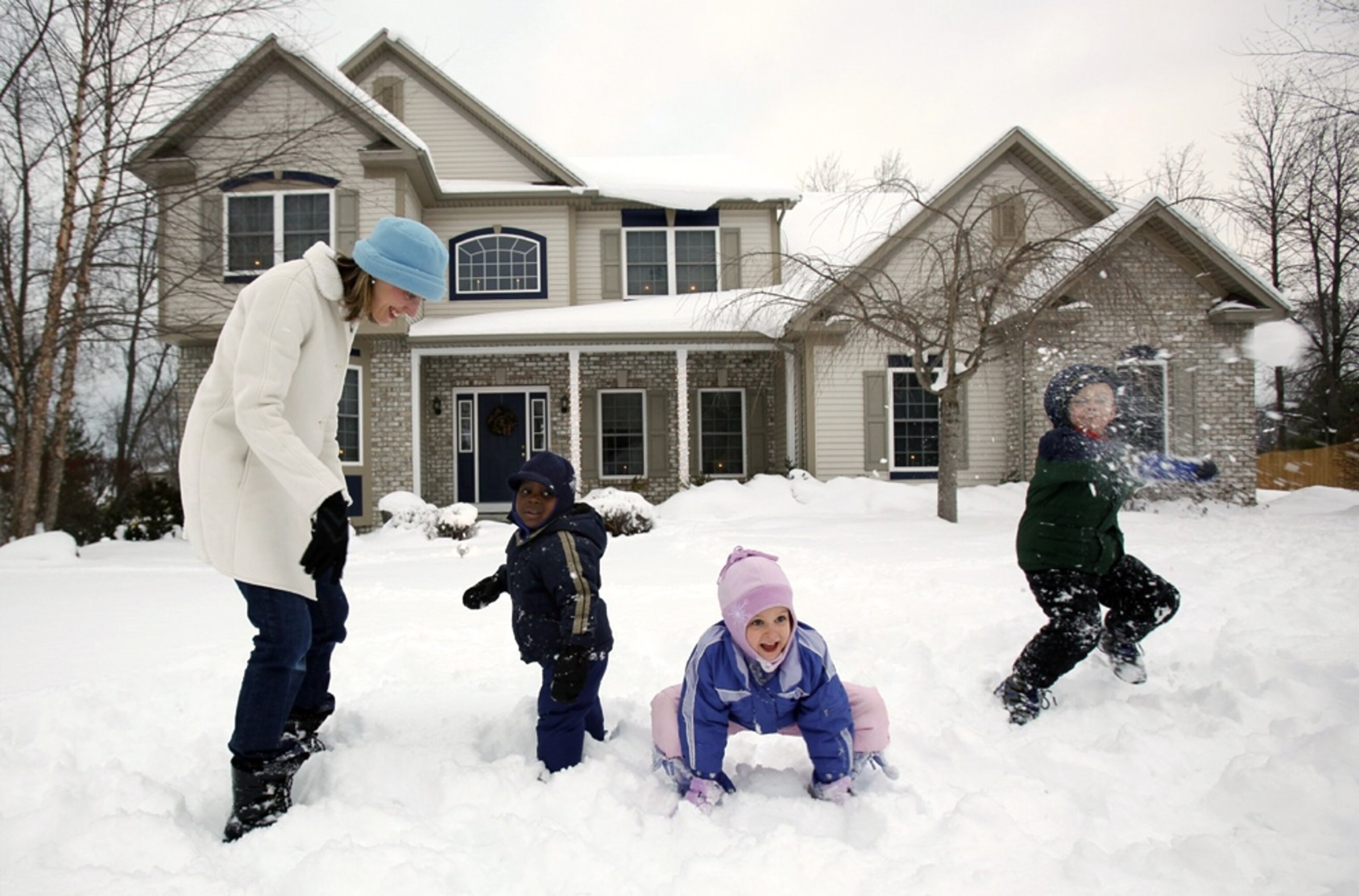 Three kids, one adopted from Haiti, play with their mother in the snowy yard in front of their New York State house -- picture from a photo gallery on the one-year Haiti-earthquake anniversary