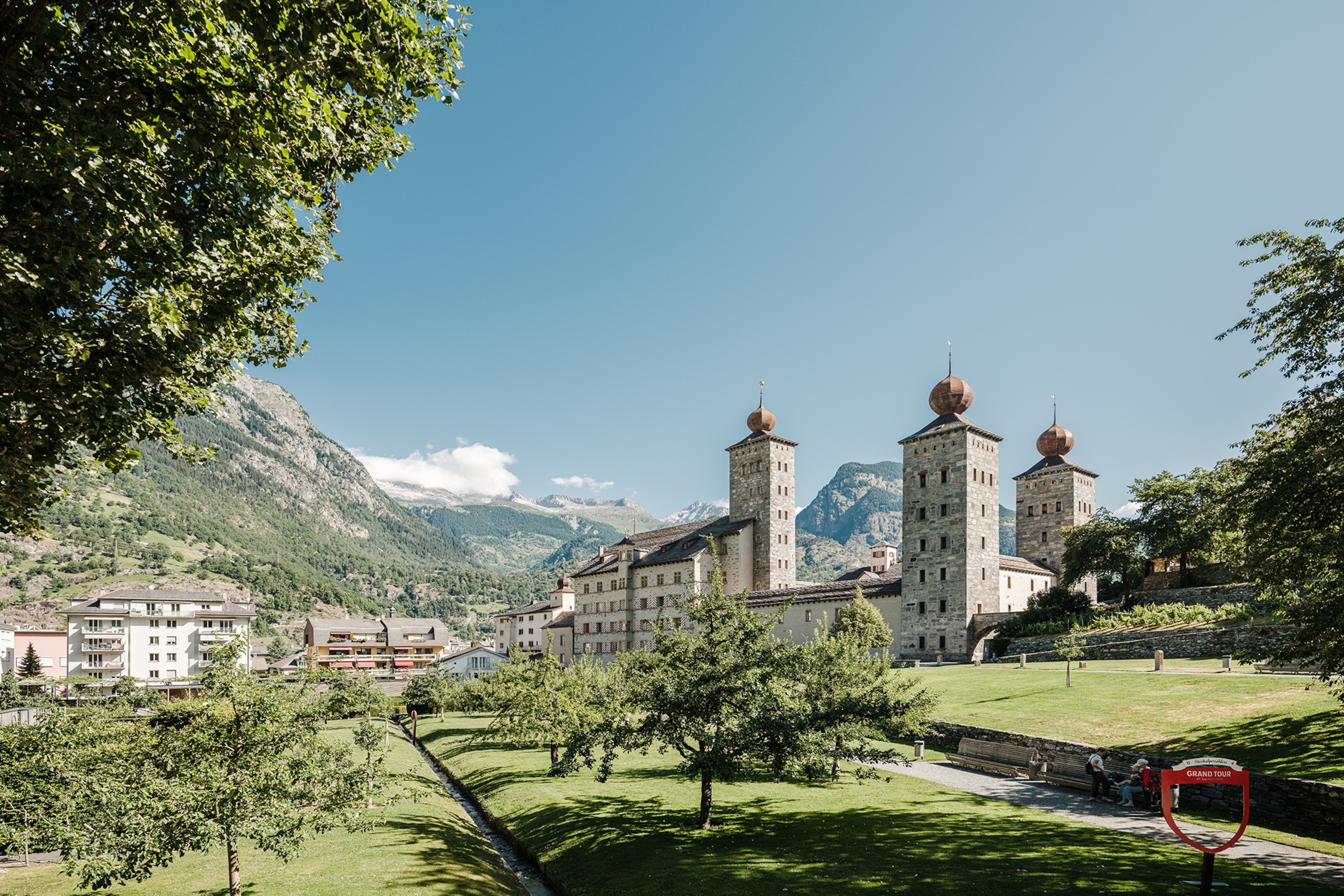 Mountains surround the ornate Stockalper Castle, with its grey towers and circular turrets.