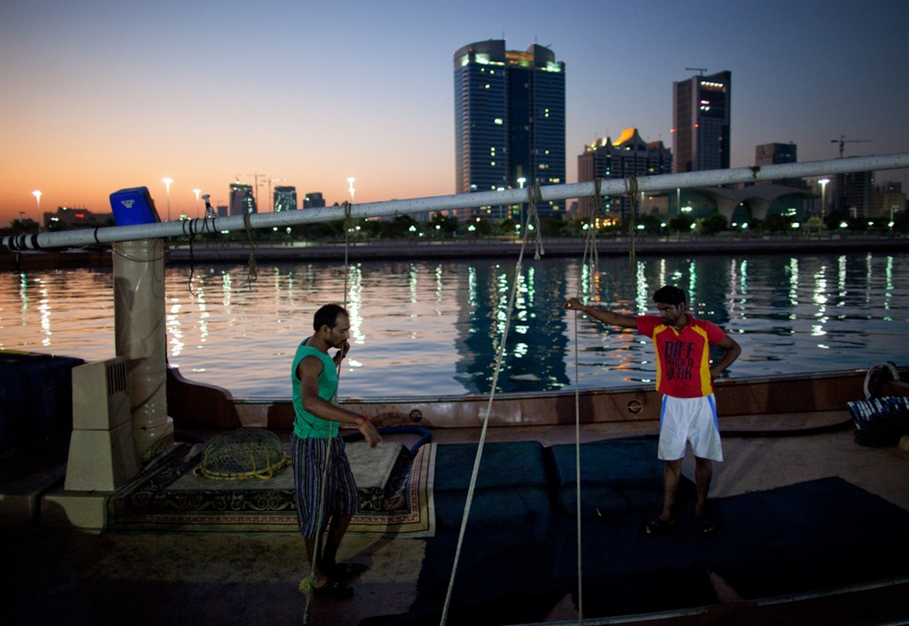 Two men standing on a fishing dhow at dawn