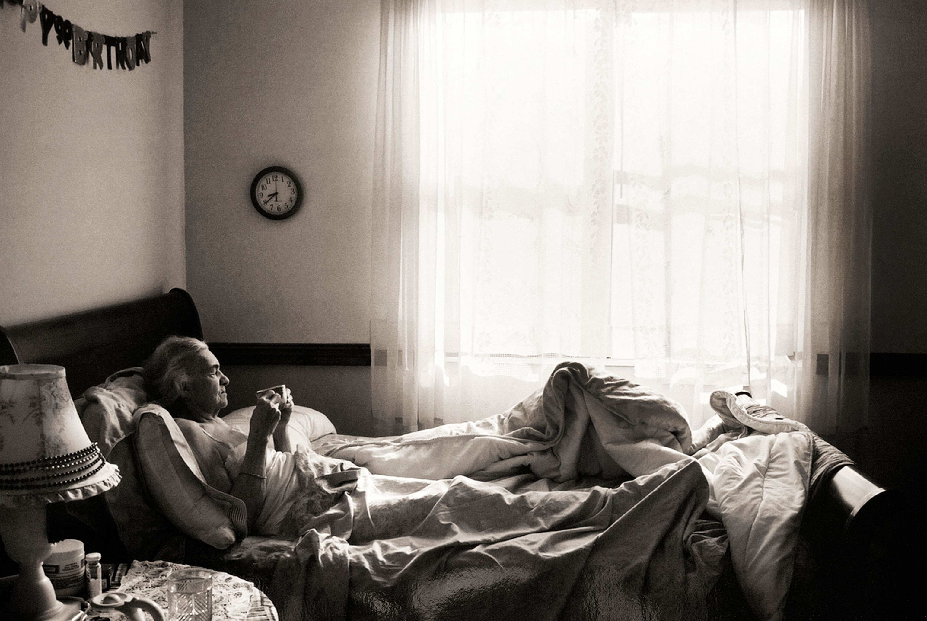an elderly woman drinking coffee in bed