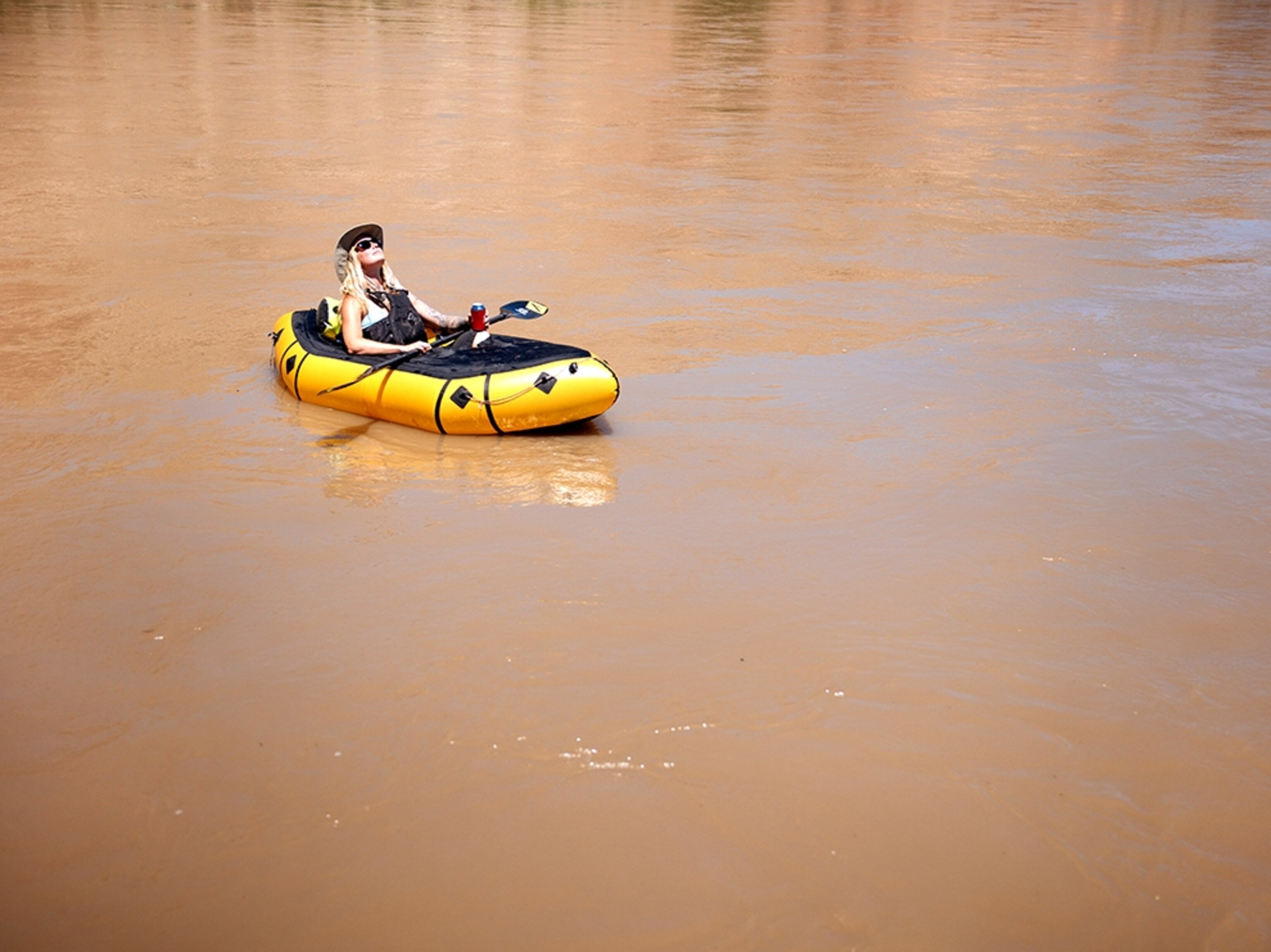 a woman floating leisurely in a inflatable boat raft down a river in Utah.