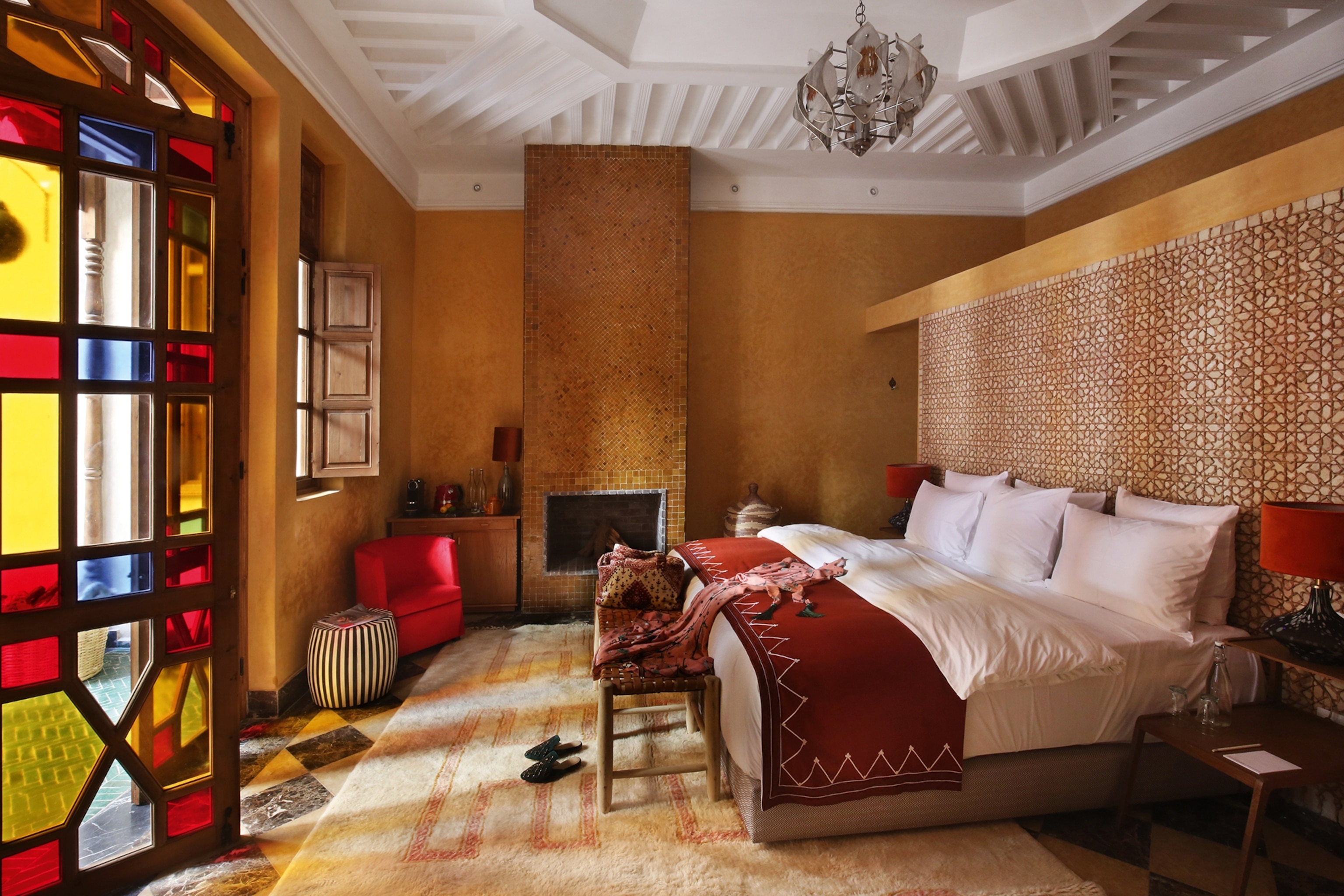 The interiors of a stylish hotel bedroom with a free-standing double bed and mosaic floor-to-ceiling windows.