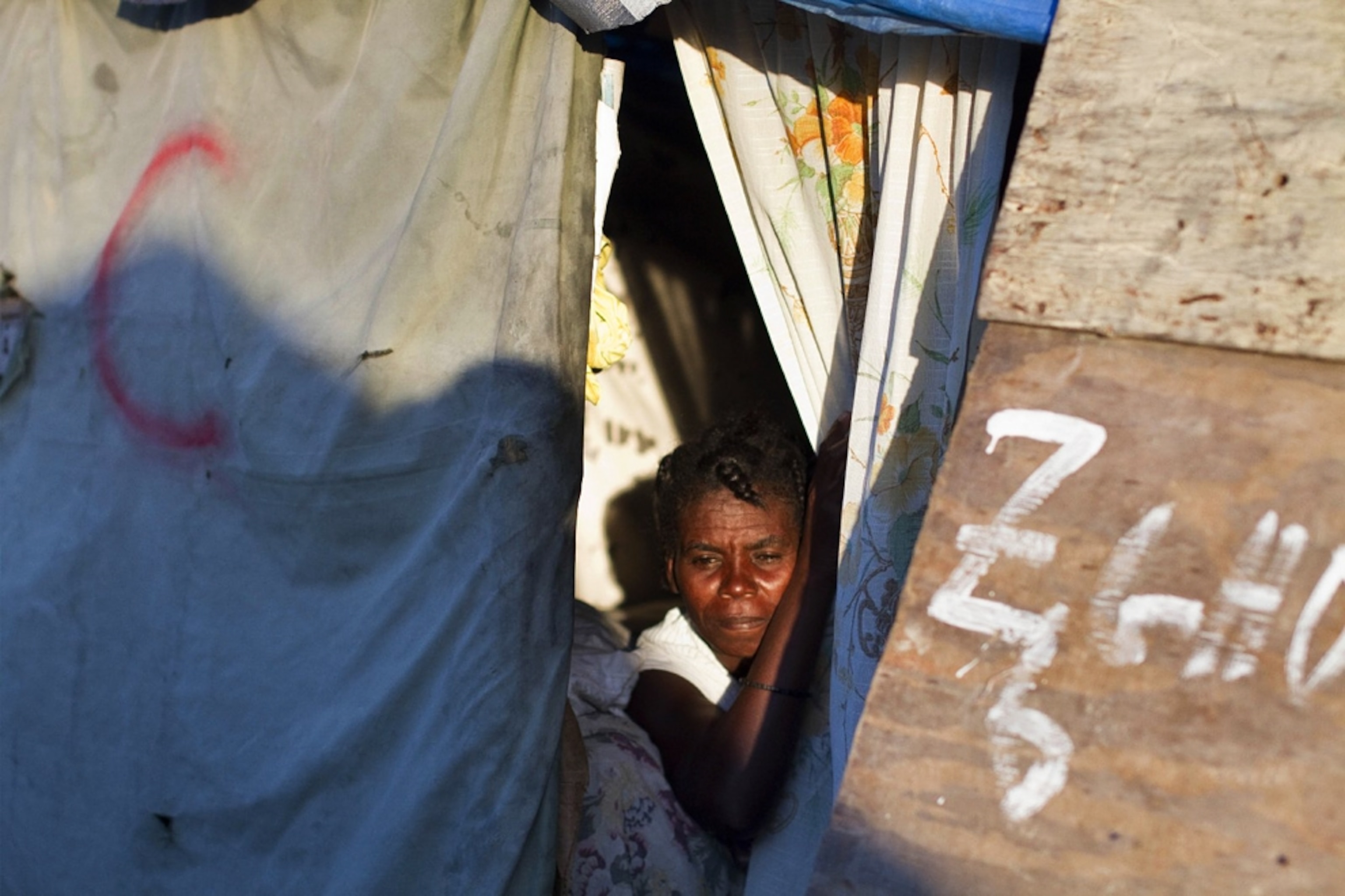 A woman peeks from the door of a tent in a Haitian refugee camp picture from a photo gallery on the one-year Haiti-earthquake anniversary