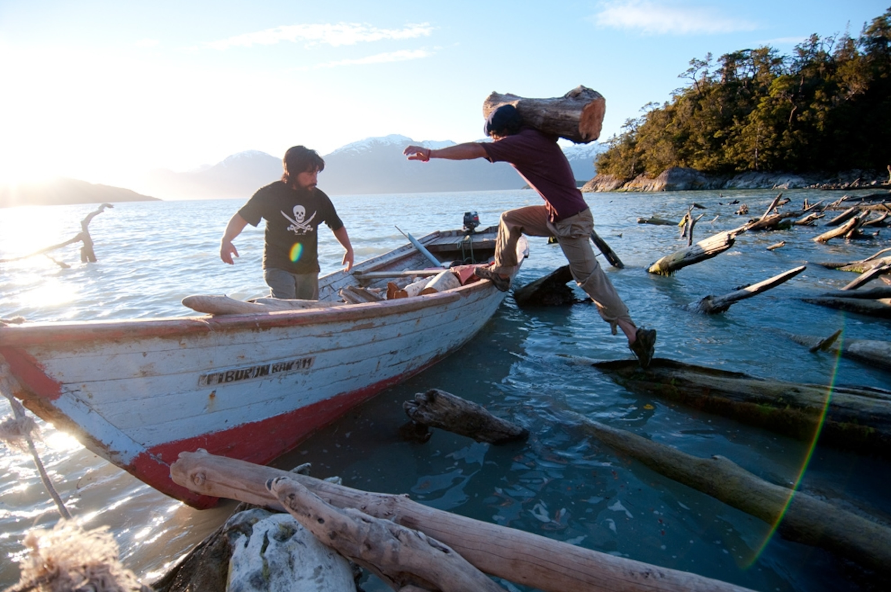 A young man jumps into a wooden boat