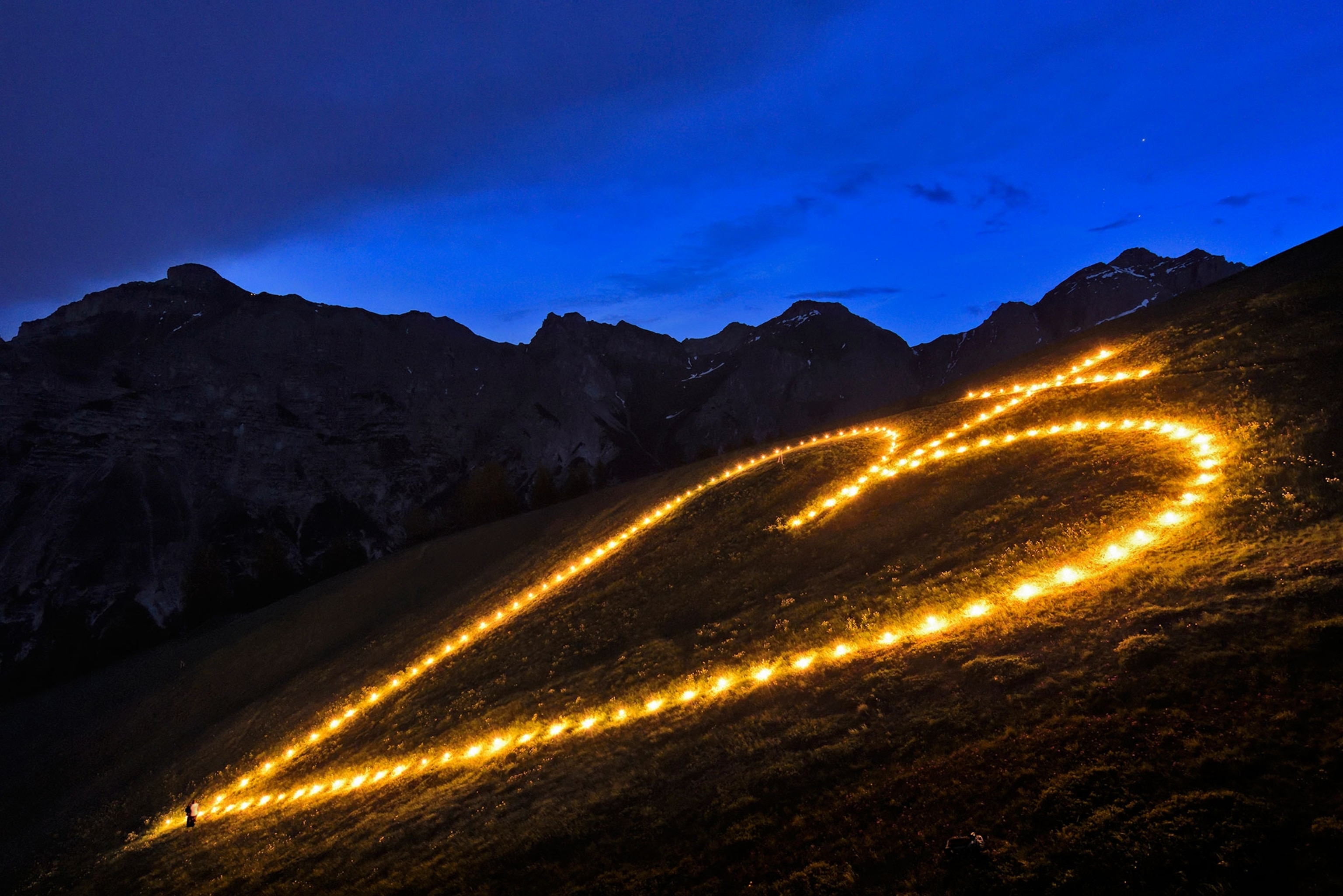 people contructing the sacred heart symbol out of fire on a mountainside