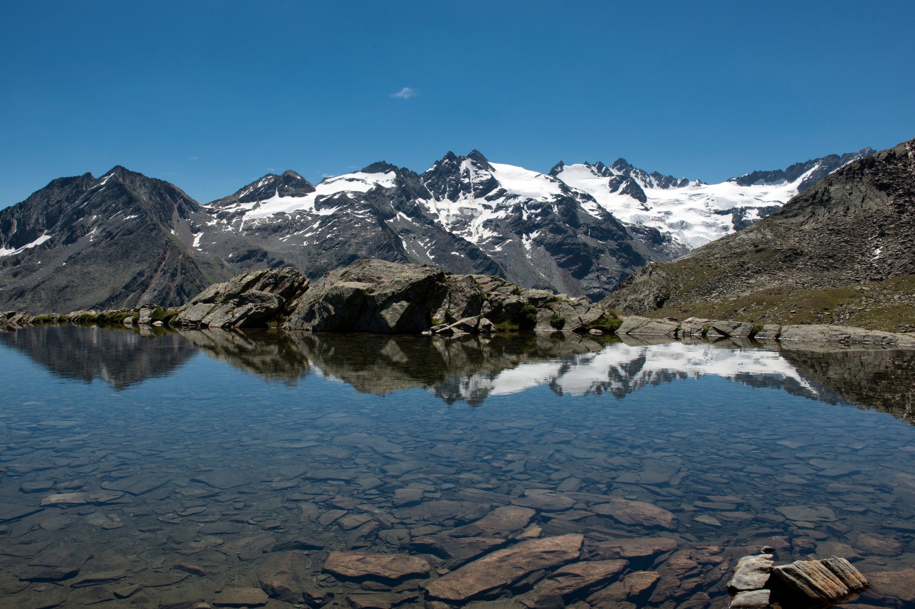 A still lake in the Gran Paradiso National Park. Snowy mountains are visible behind.