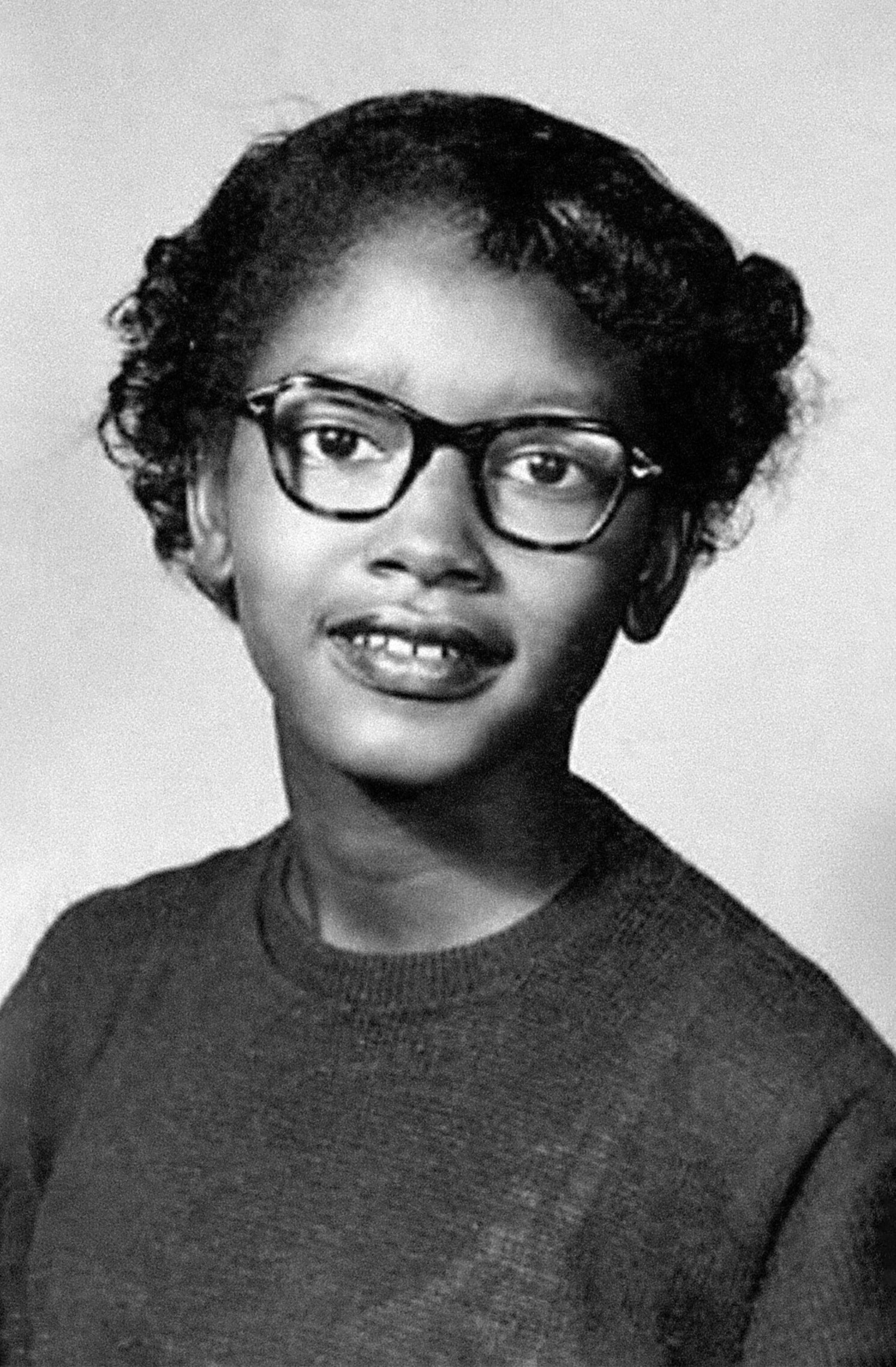 A young African-American girl wearing glasses, smiling for the camera