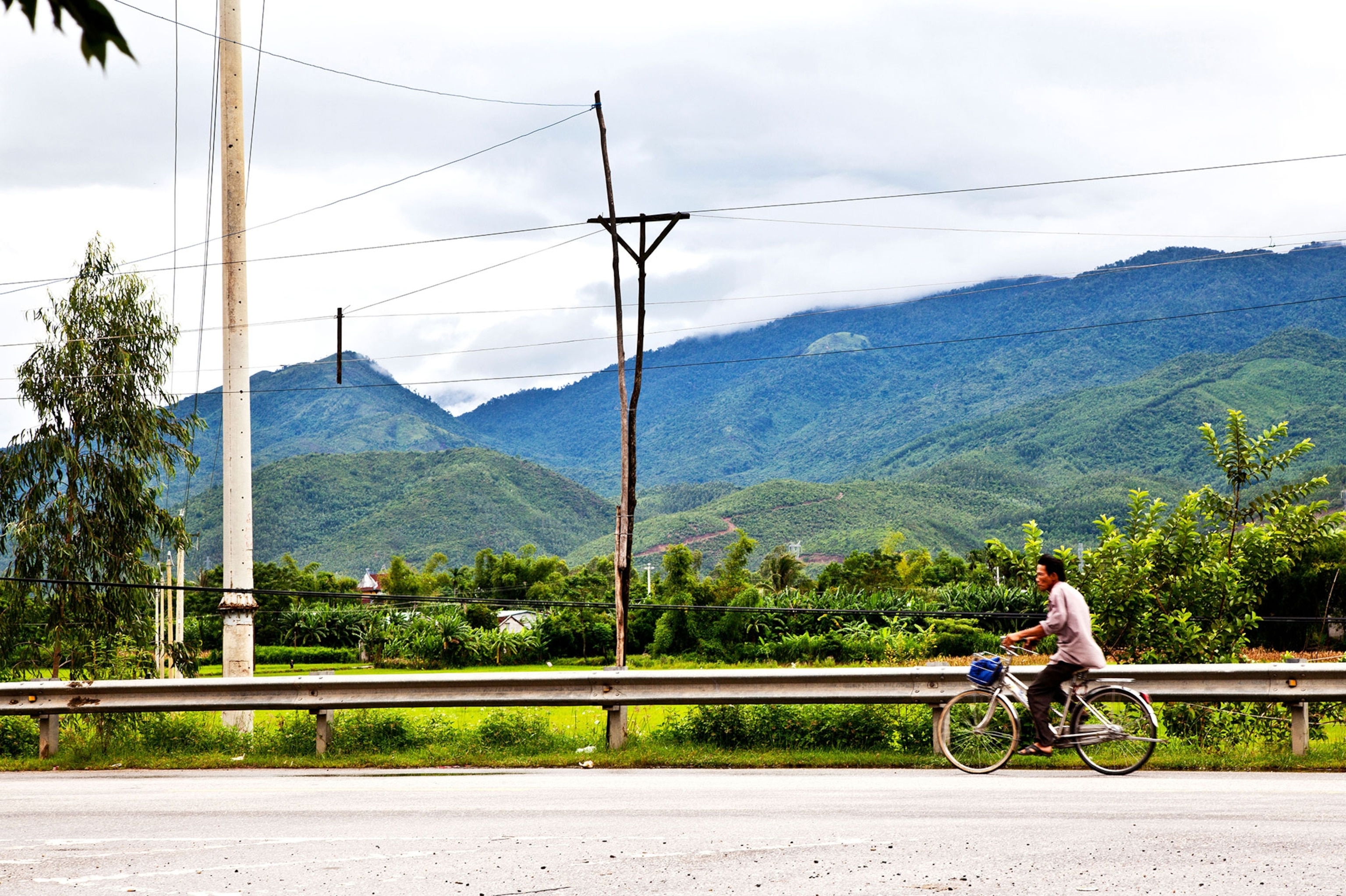 a man riding a bicycle along the Ho Chi Minh trail in the mountains of Vietnam