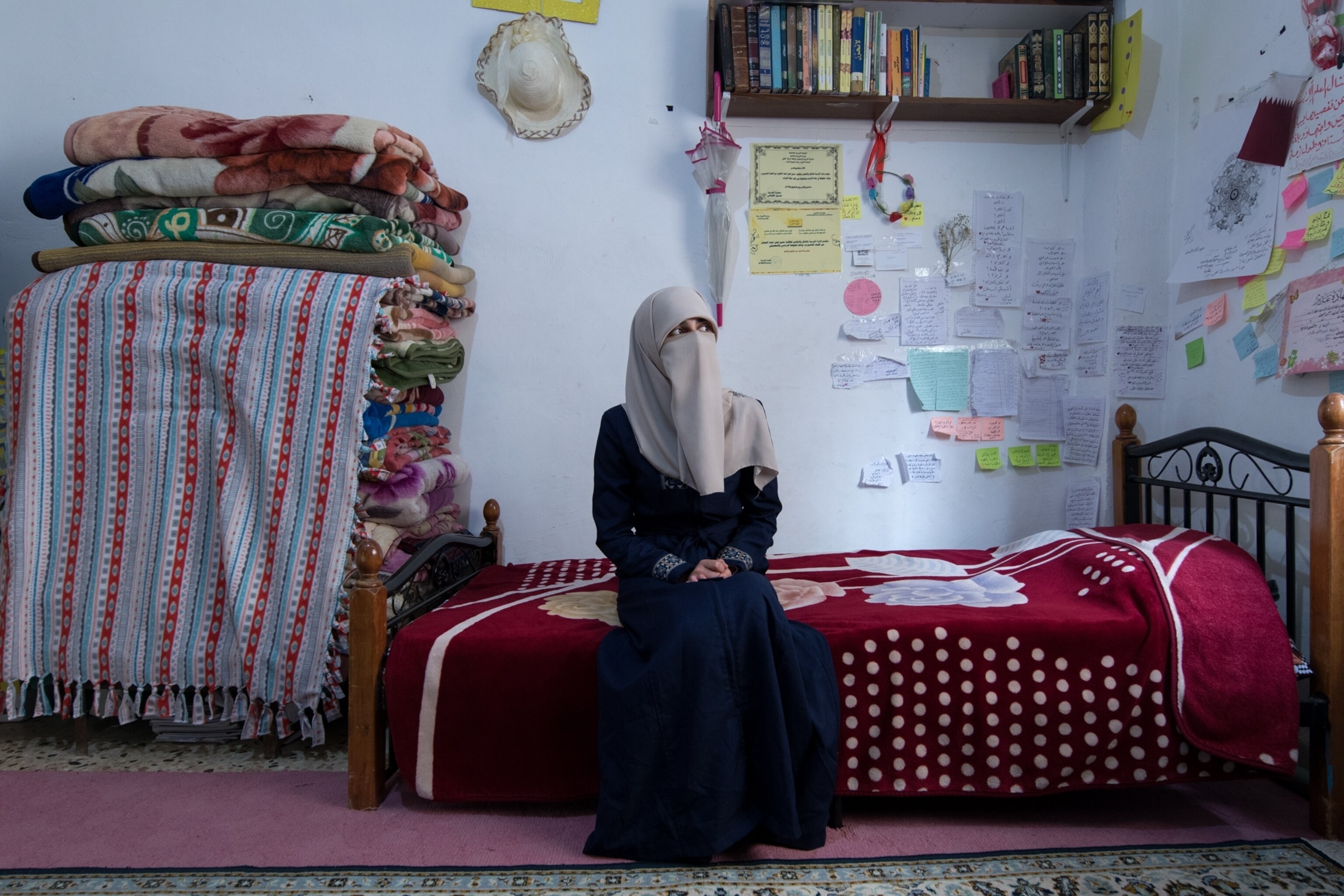 a covered woman sitting on her bed in a colorful room