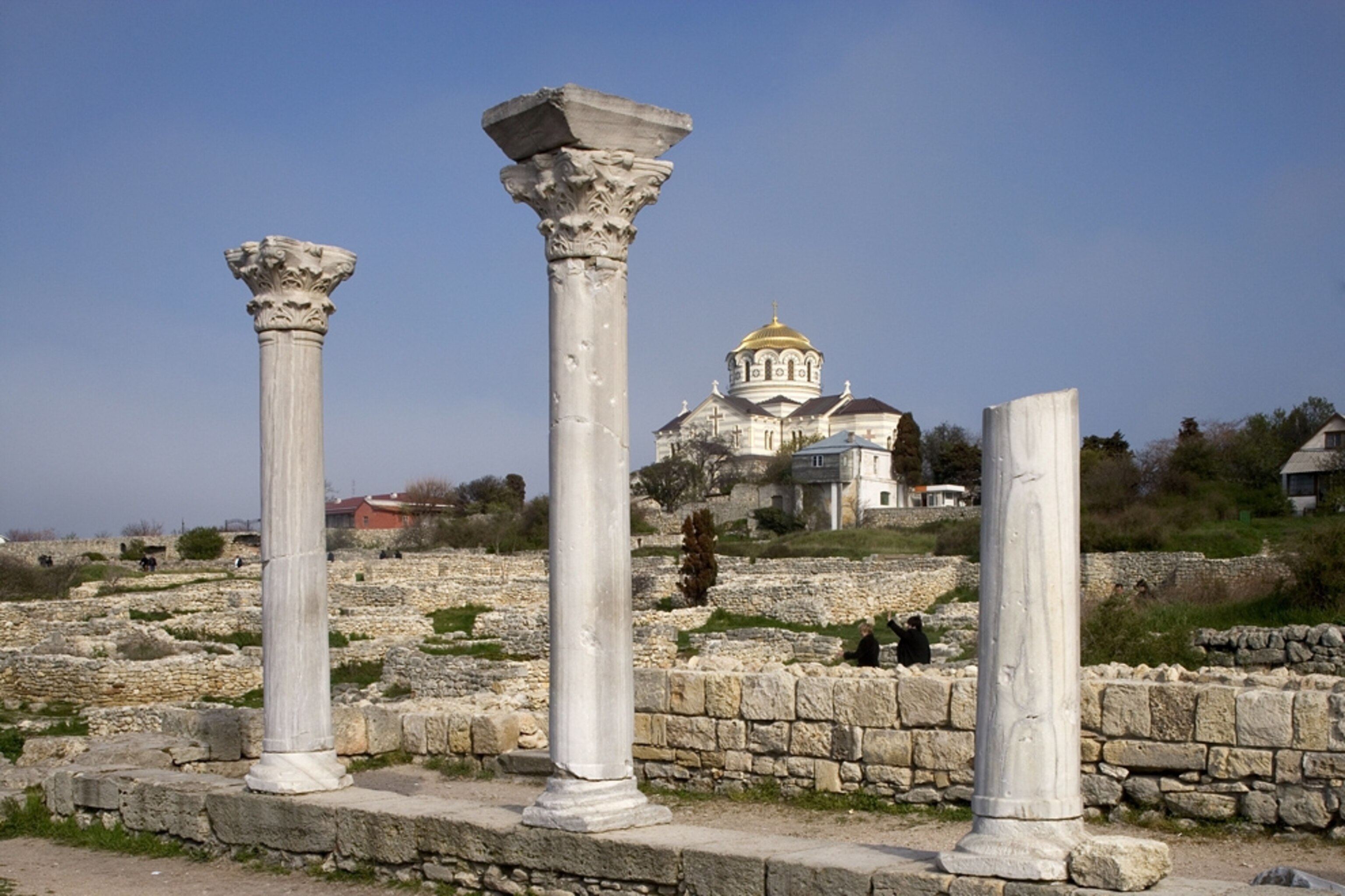 Picture of columns from a ruined church in Ukraine, with a recently renovated building in the background.
