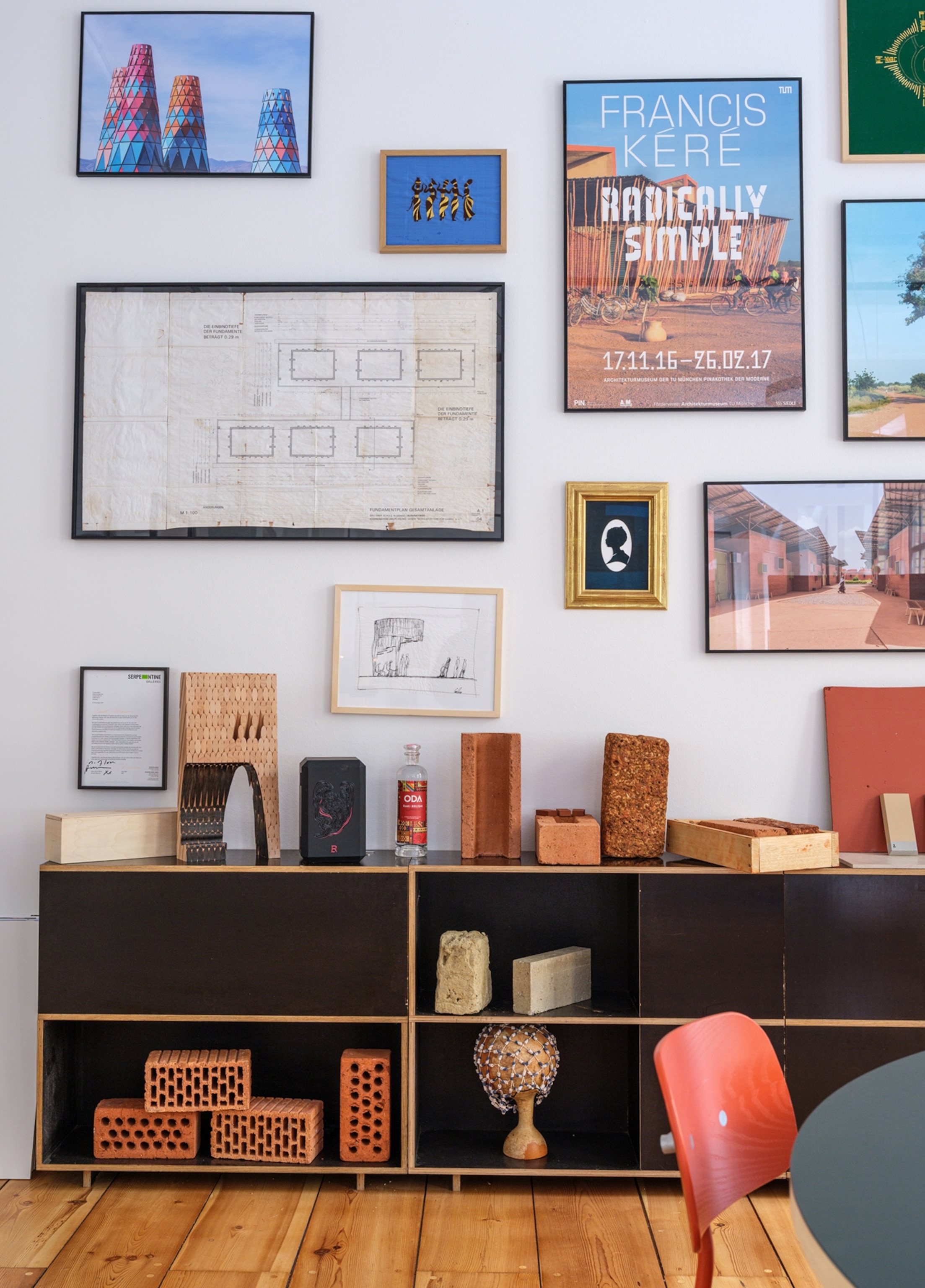 A view of a wall that has many images hanging and a full bookshelf against it.
