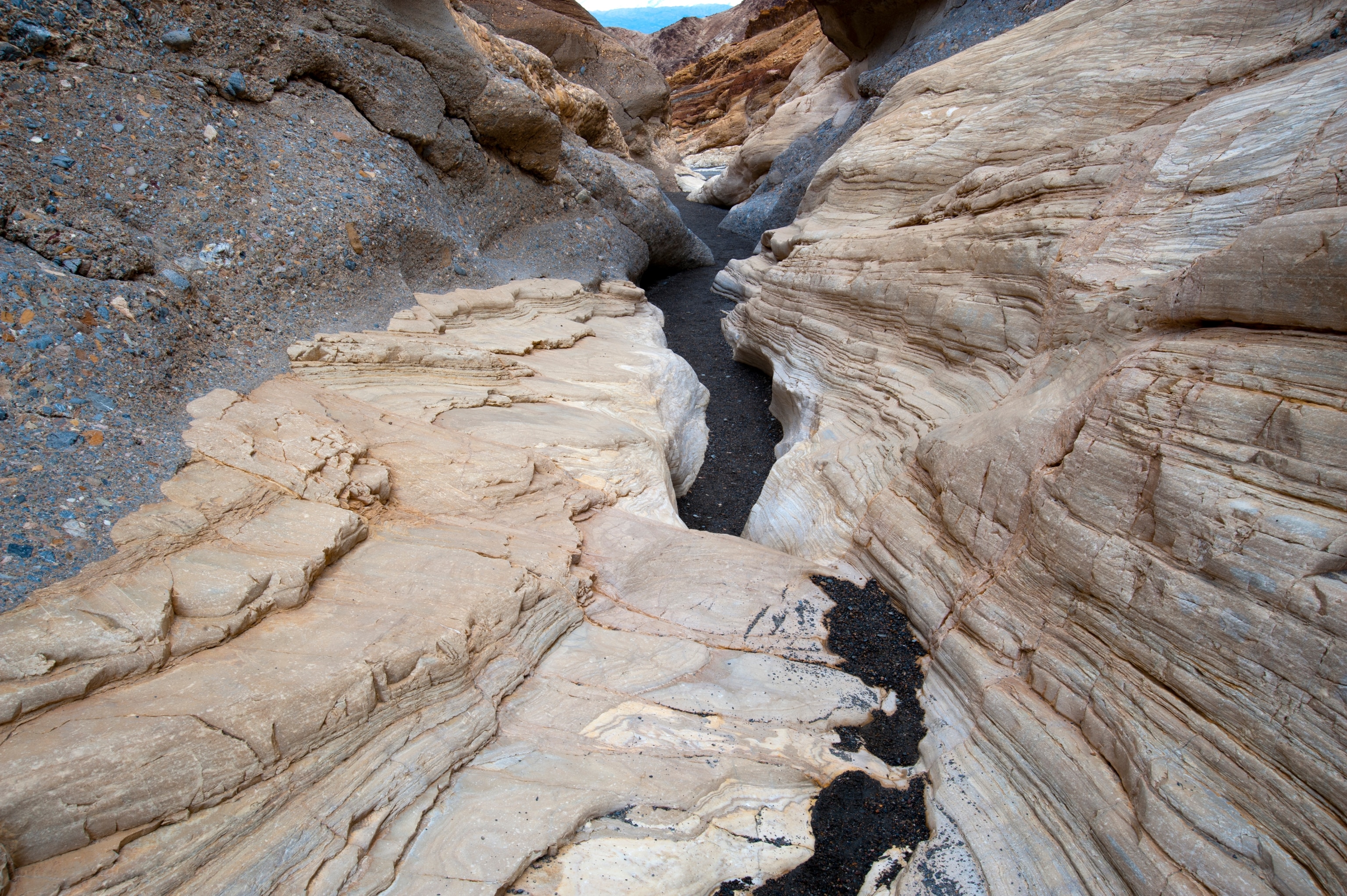 An asphalt trail leads through the smooth white polished marble walls in Mosaic Canyon.