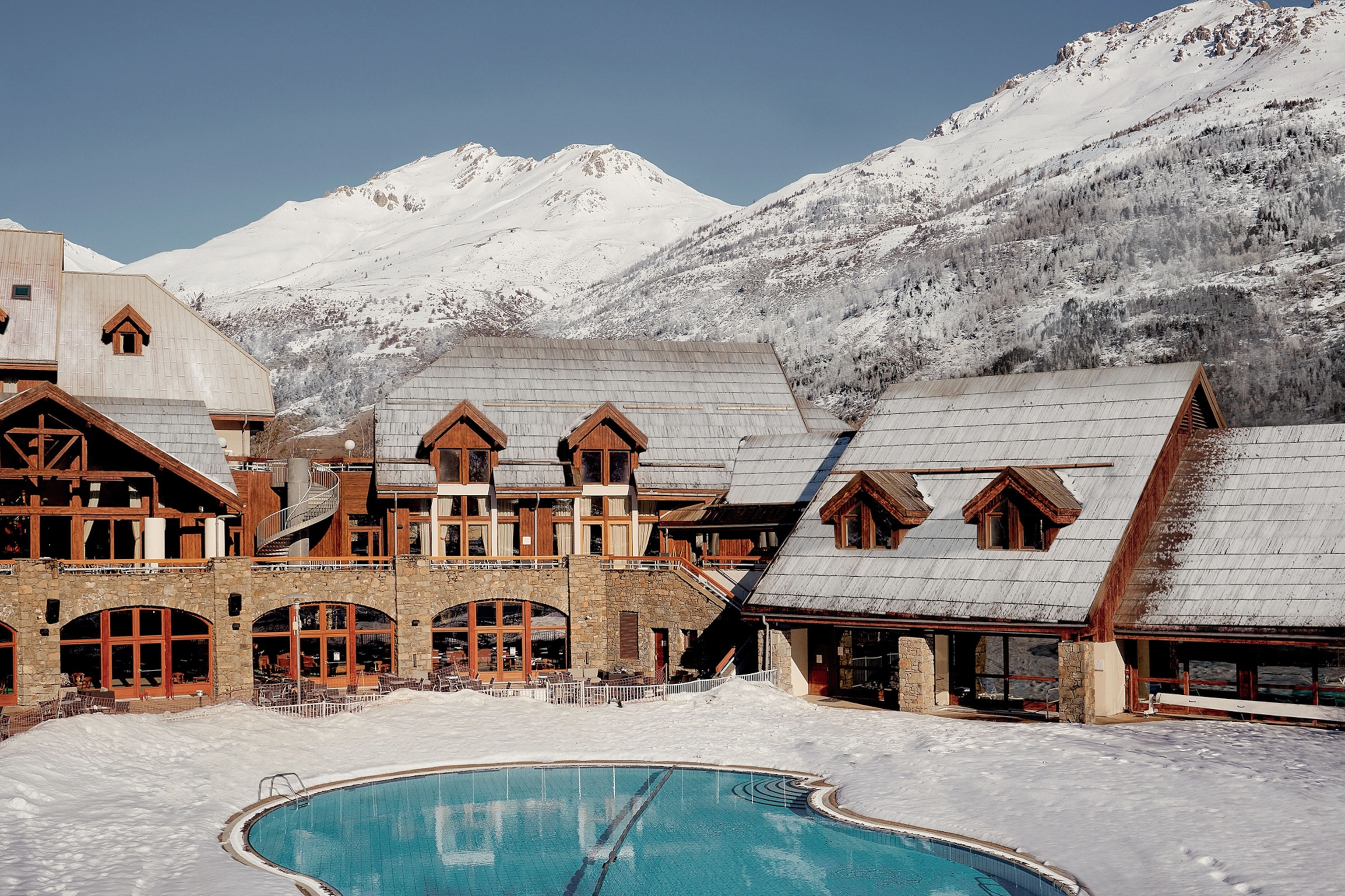 A charming mountain chalet hotel with a pool set into a mountain valley.