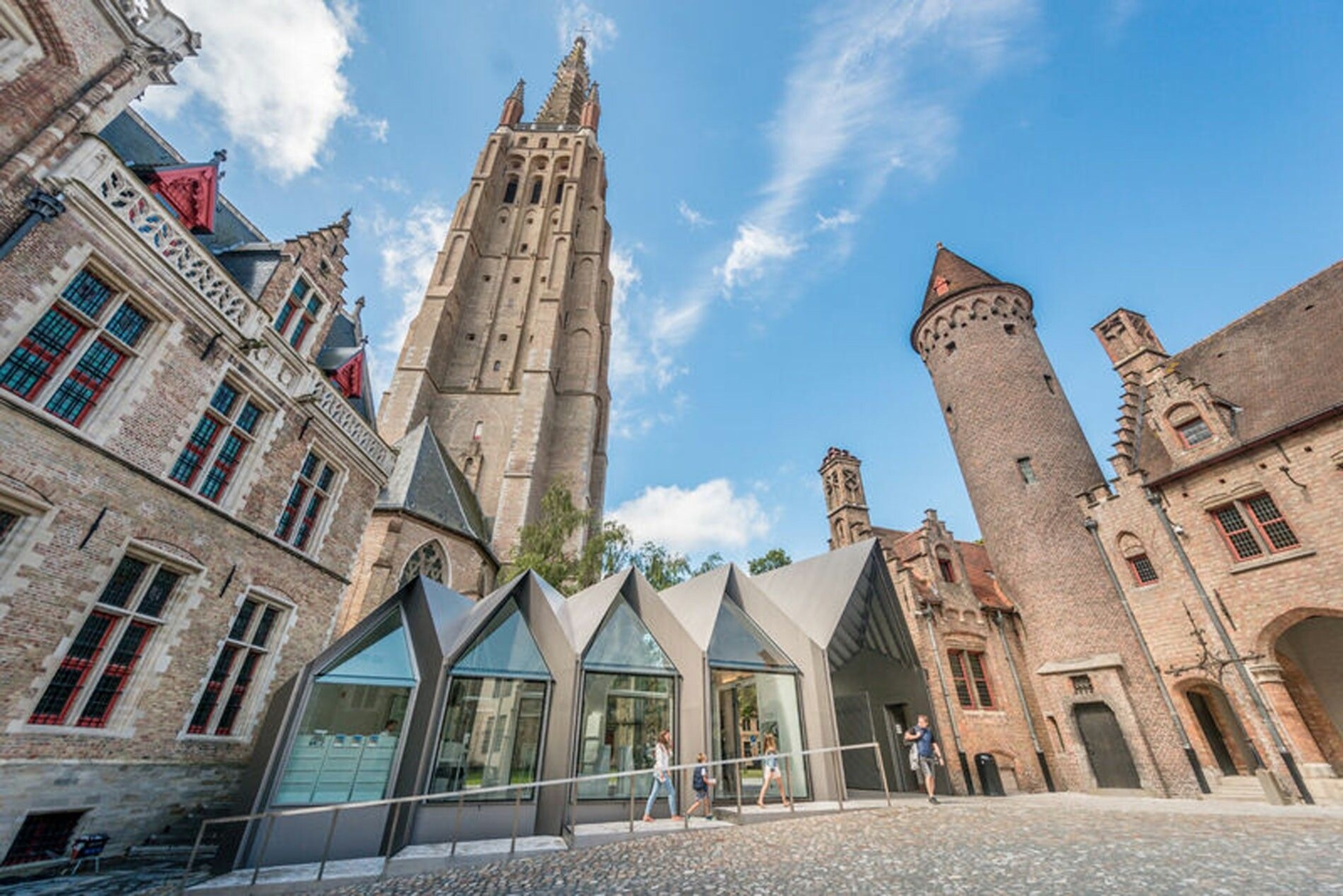People enter the Gruuthuse Museum, a dramatic building with two tall towers.