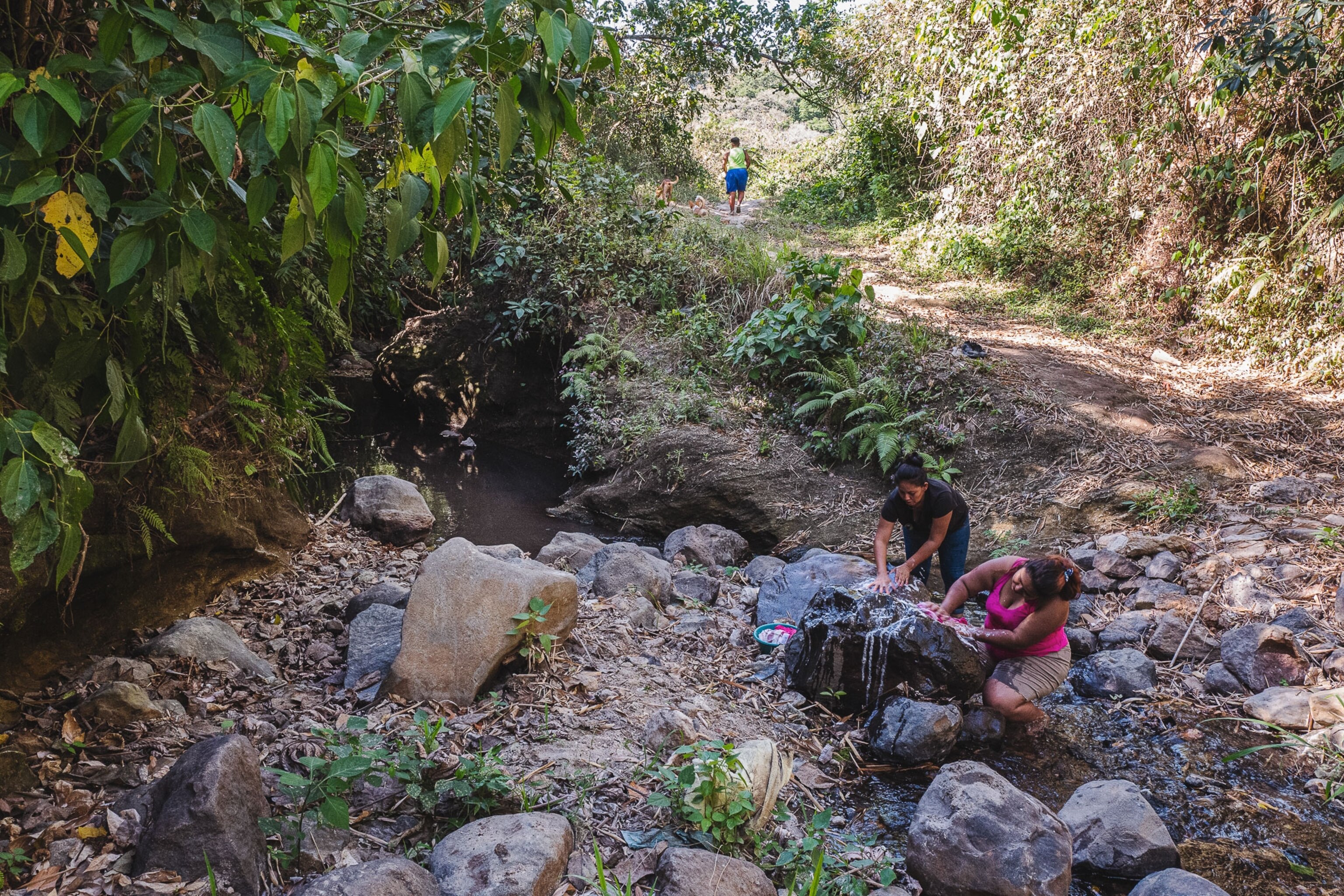 women wash clothes in a river in El Salvador