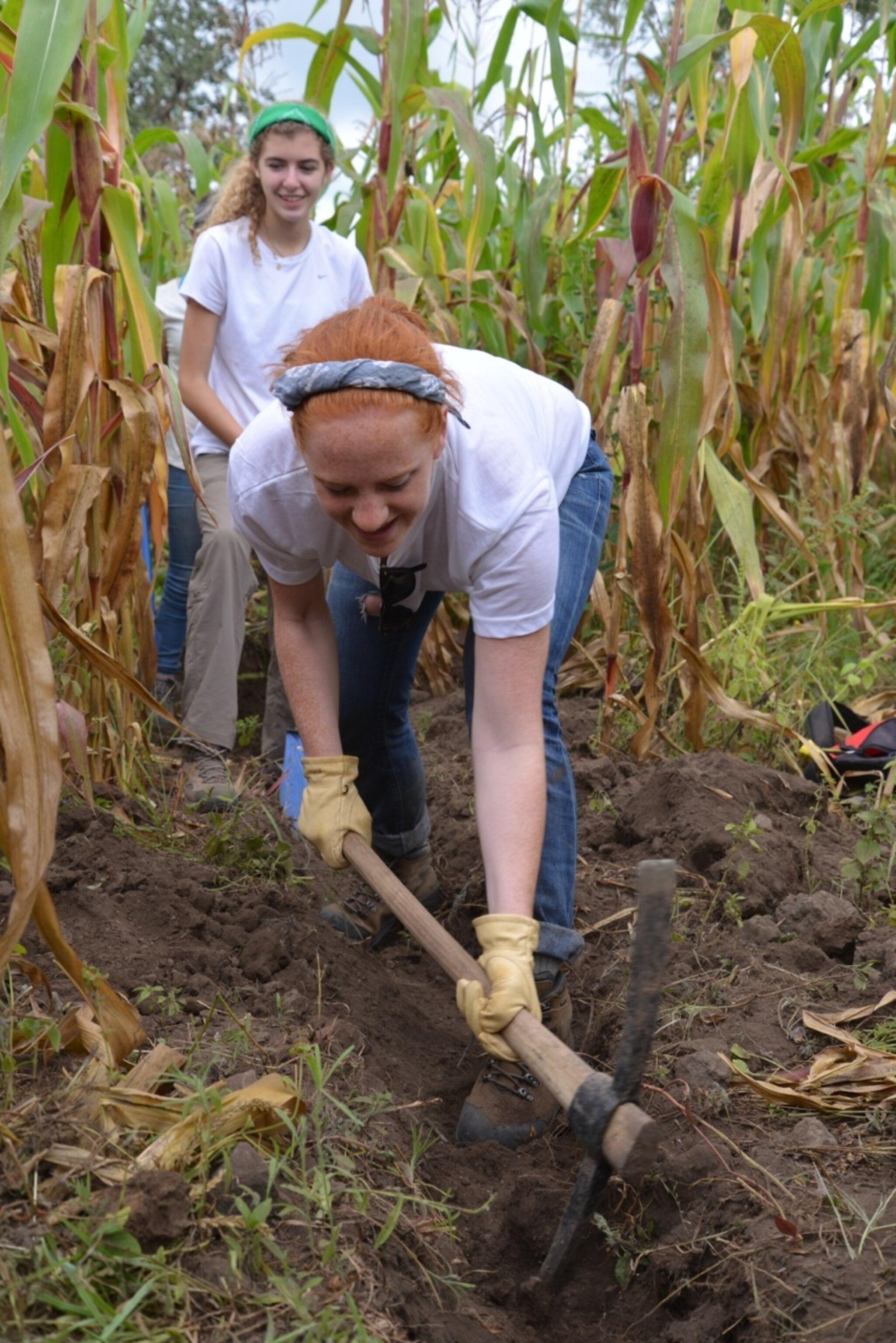 While Lauren Deutser cheers from behind, Sheila O'Neill pounds the rocky soil, breaking up the rocks buried beneath. (Photo by Andrew Evans, National Geographic Traveler)