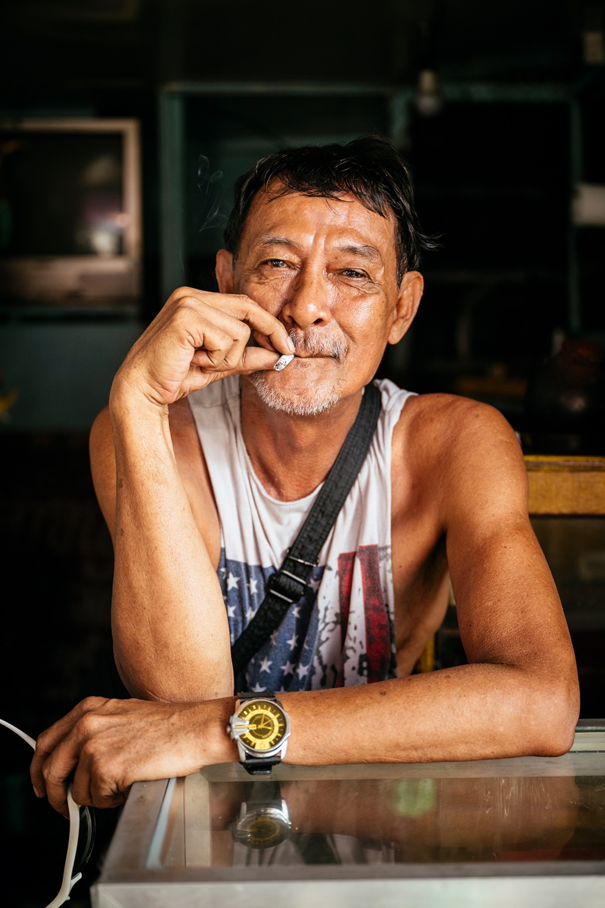 A portrait of a middle-aged man with a cigarette hanging out of the corner of his mouth.