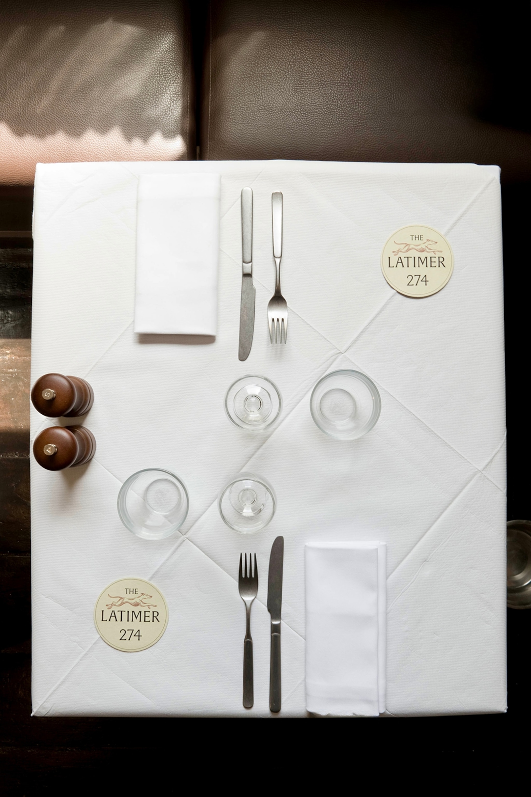 A neatly set table with white tablecloths shot from above.