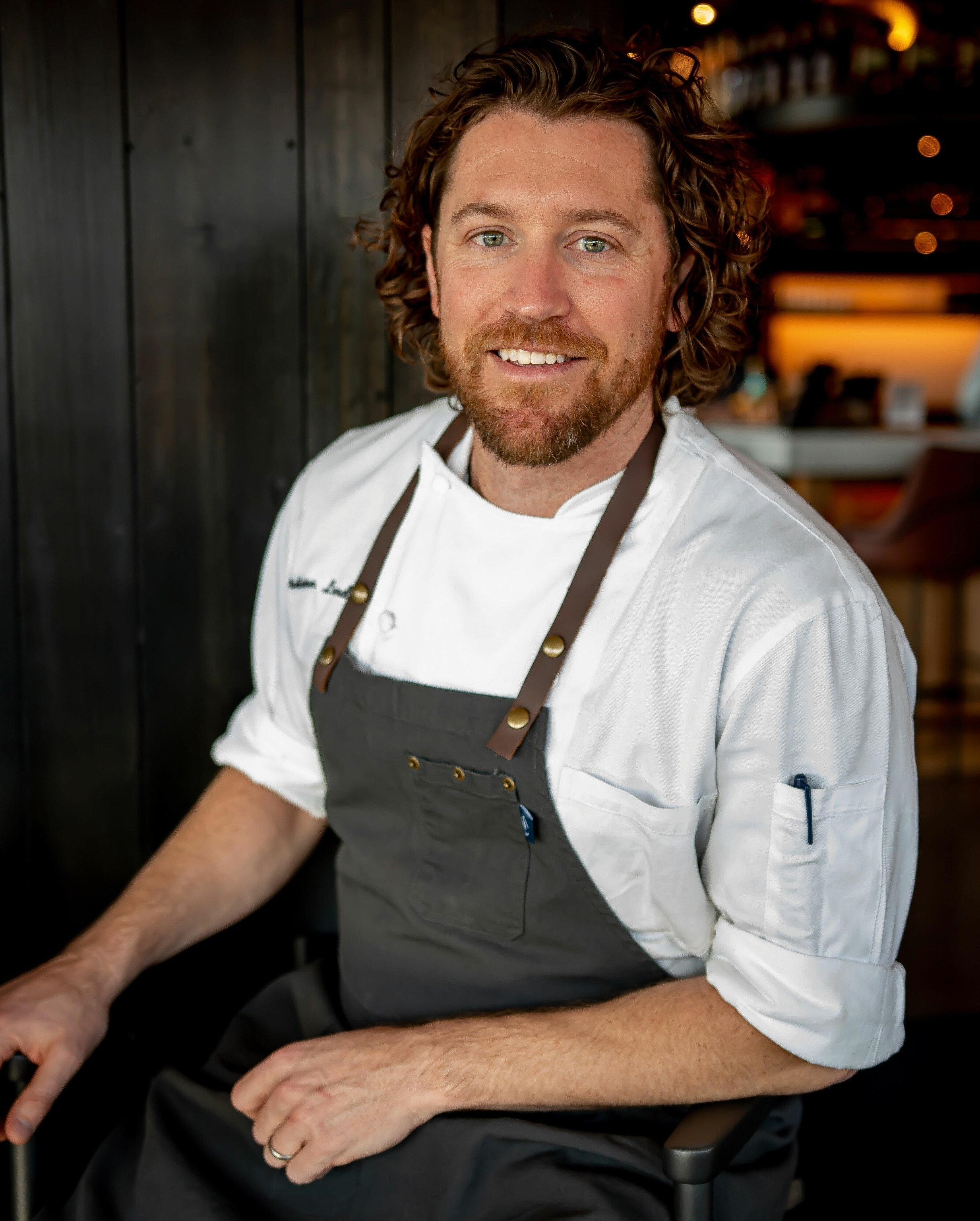 Brian Landry. He is wearing a charcoal coloured apron over a white chef's uniform.