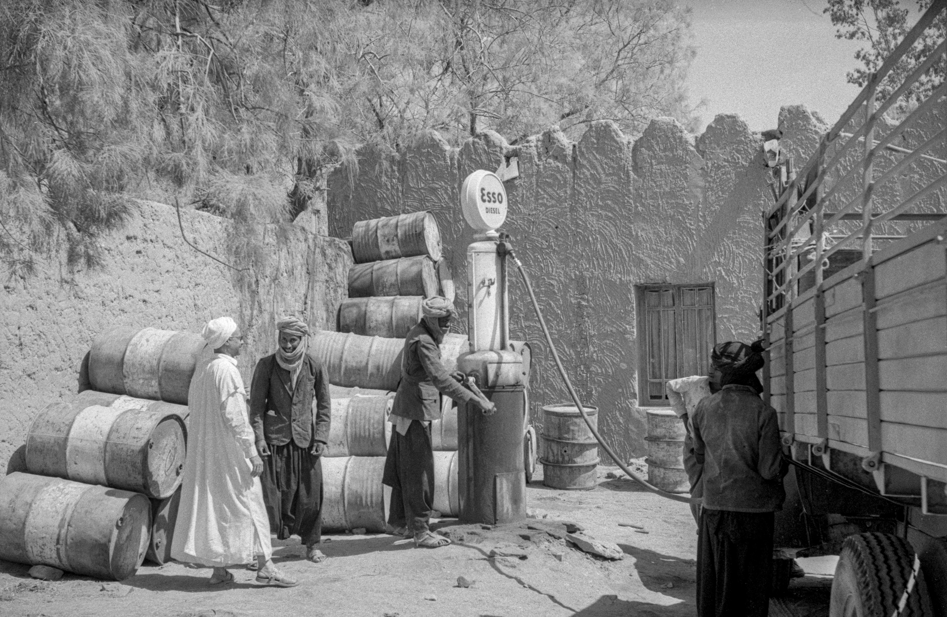 People stand by a gas pump and barrels
