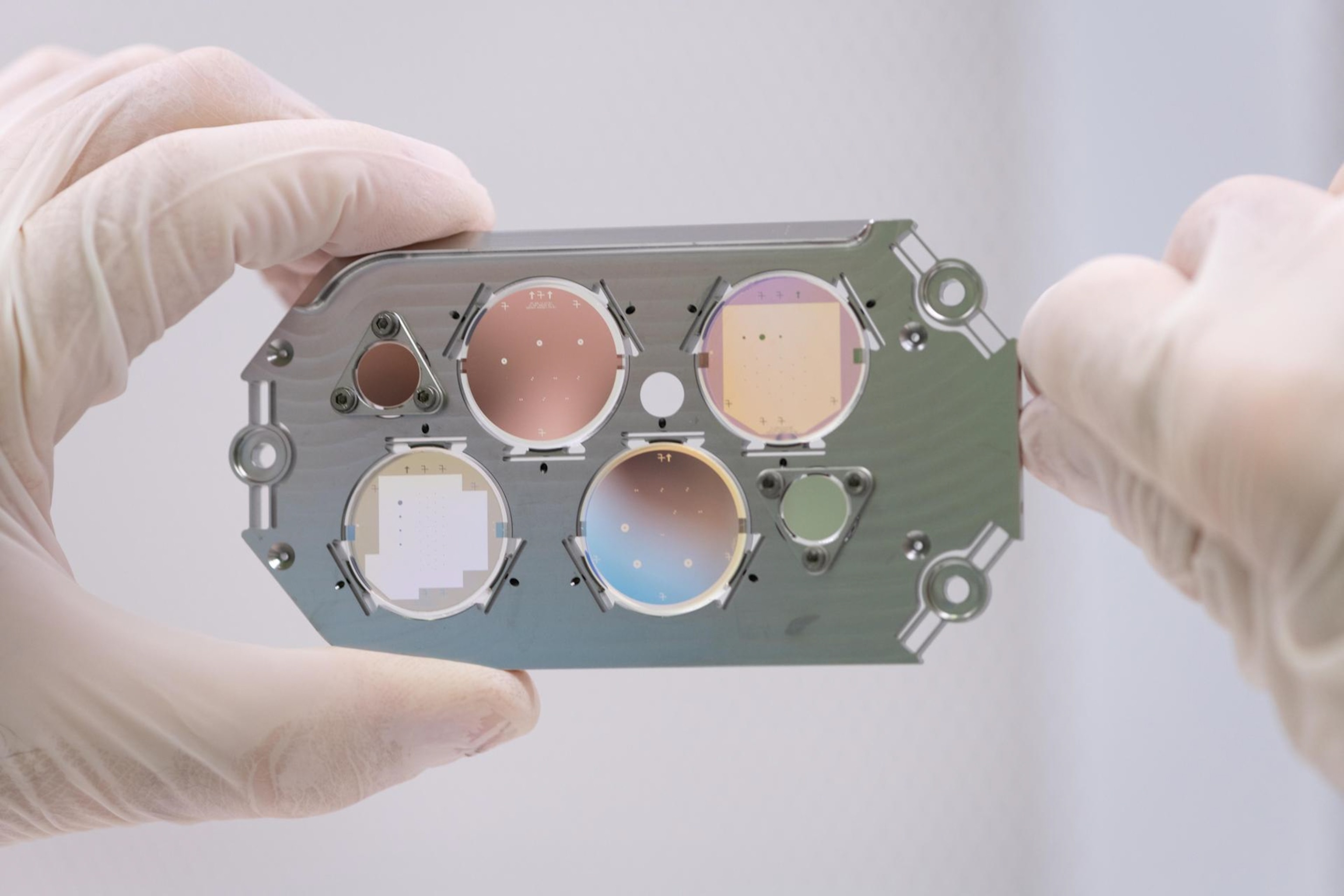 Focal plane with glass lenses being held by two hands in white gloves.