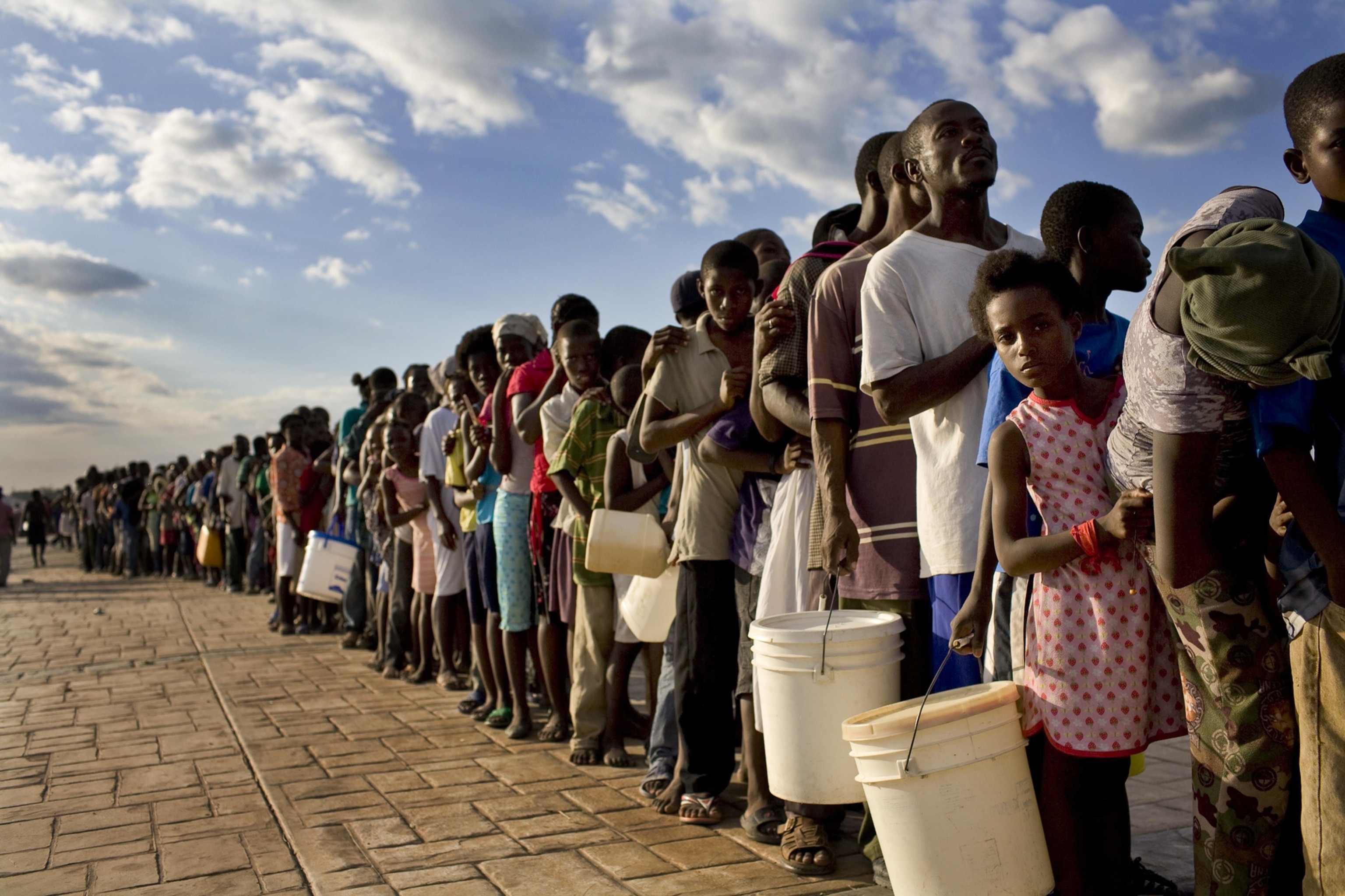 people waiting in long lines for food and water distribution.