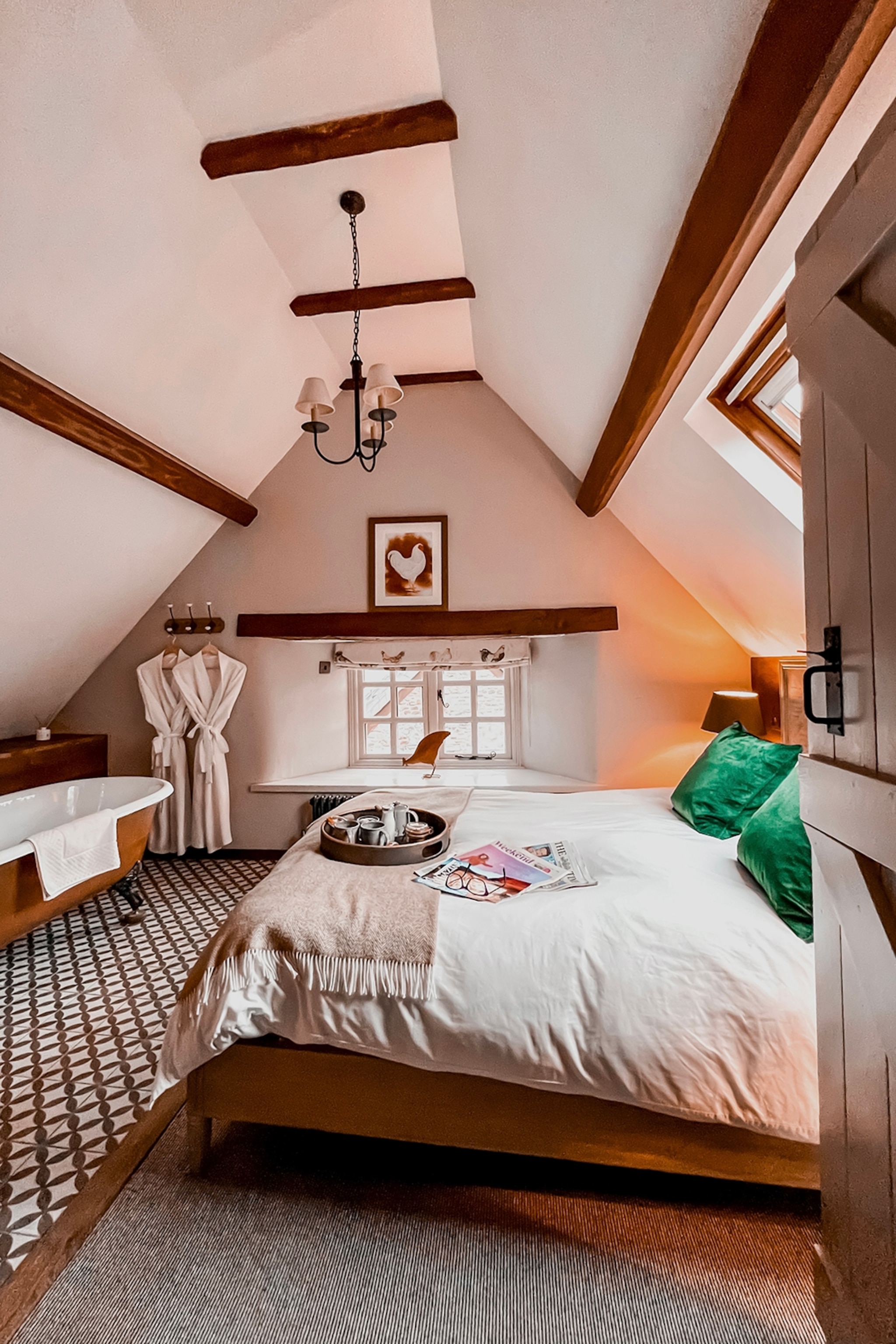 The interiors of a barn hotel bedroom with exposed wooden beams and country-chic decorations.